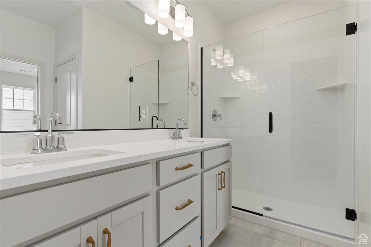 Bathroom with walk in shower, tile floors, and double sink vanity