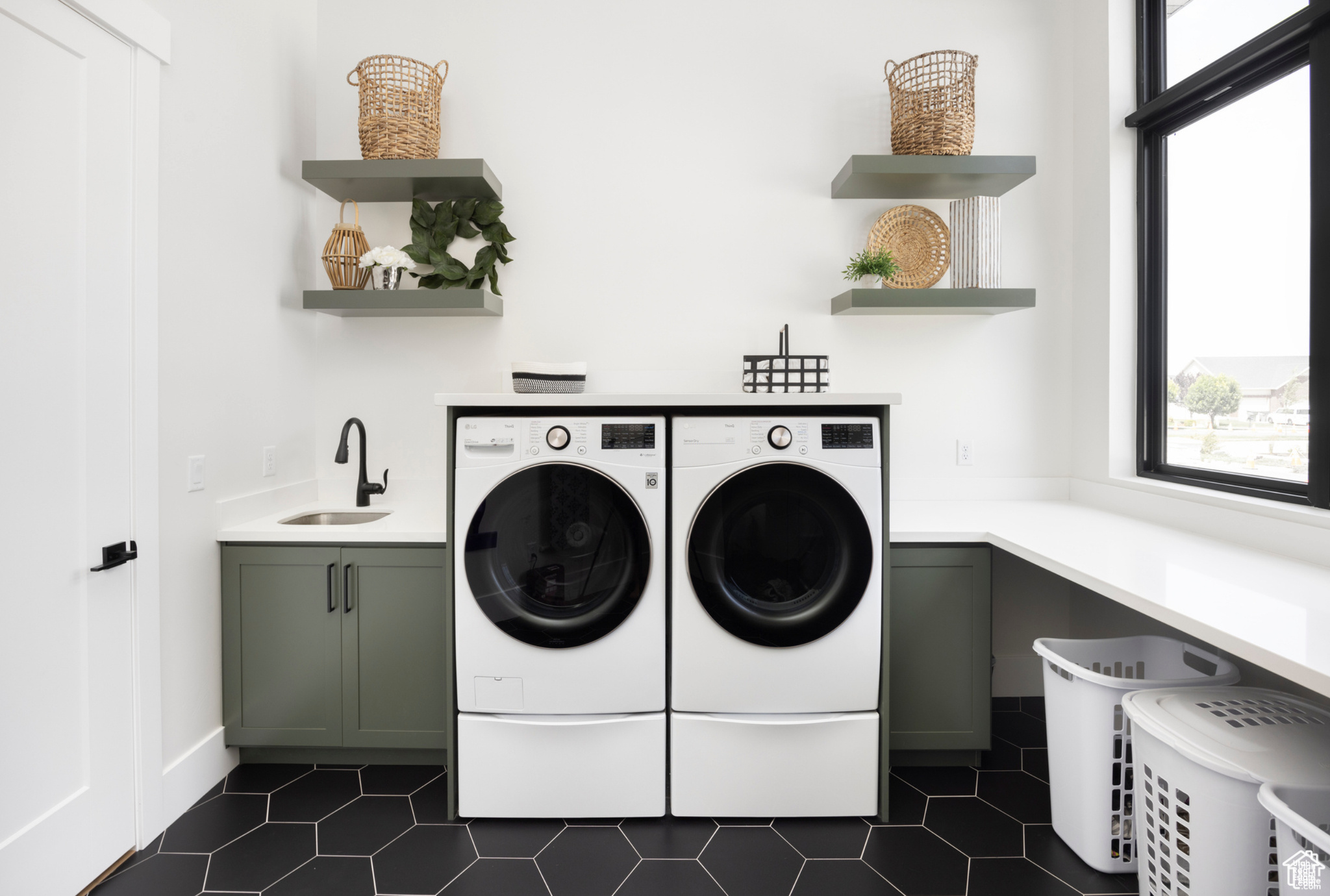 Laundry room featuring cabinets, sink, washing machine and dryer, and dark tile flooring