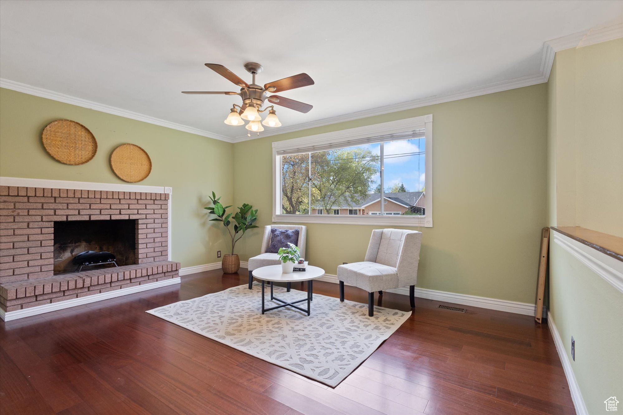 Sitting room featuring ceiling fan, a fireplace, dark wood-type flooring, and crown molding
