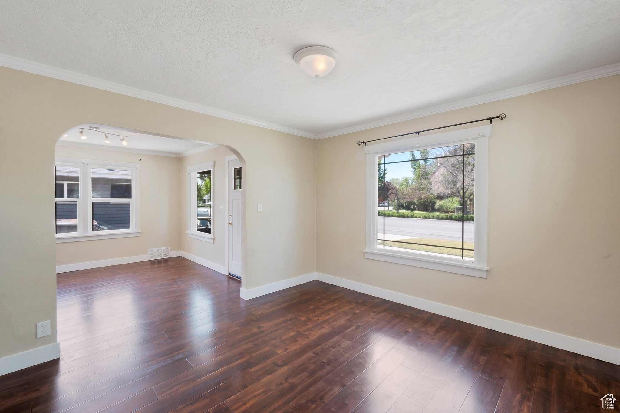 Empty room with crown molding, hardwood / wood-style flooring, and plenty of natural light