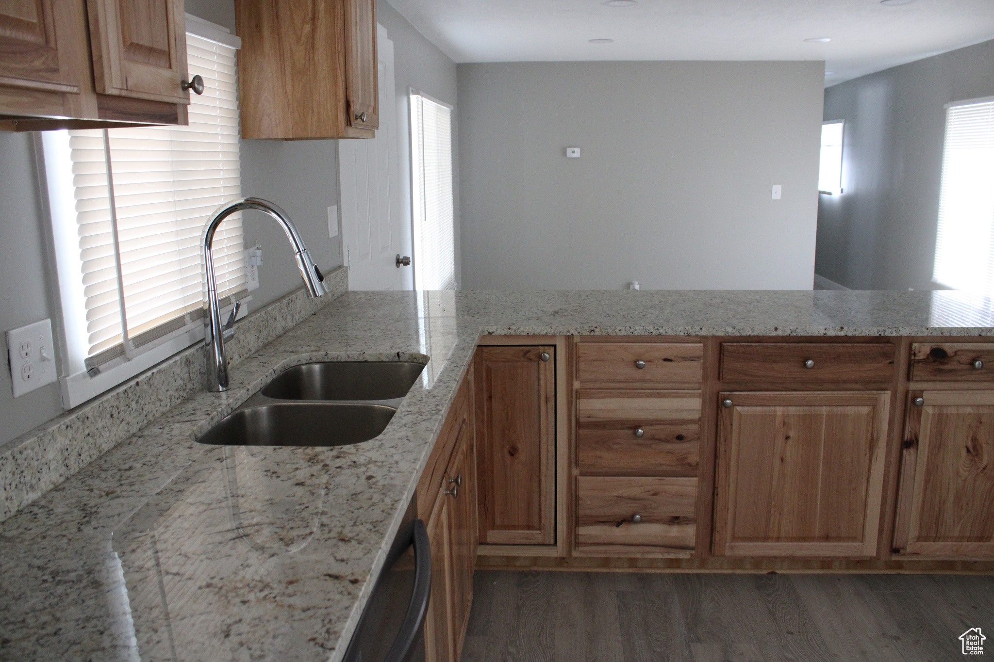Kitchen with sink, kitchen peninsula, dark hardwood / wood-style floors, and light stone countertops