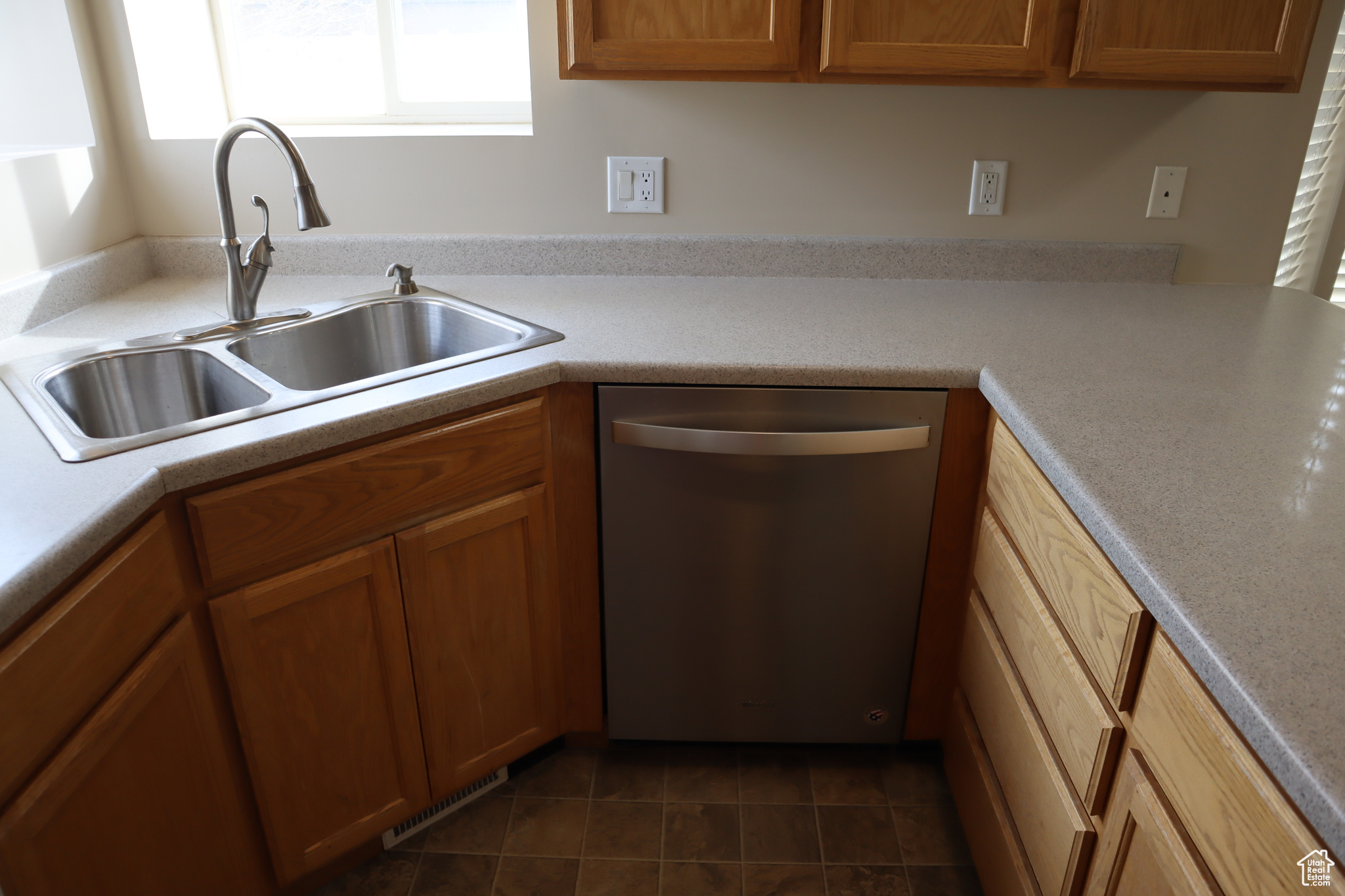 Kitchen with dark tile floors, dishwasher, and sink
