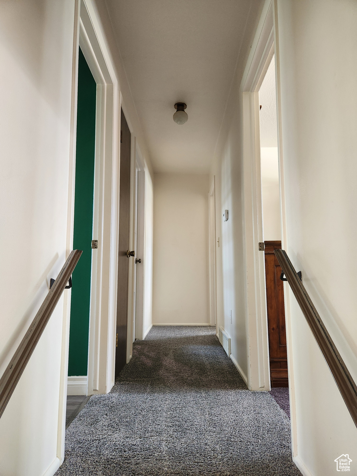 Hallway featuring dark colored carpet