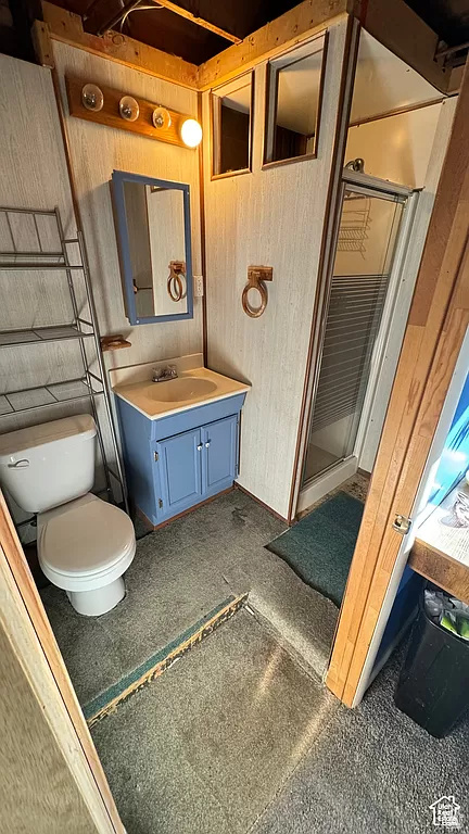 Bathroom featuring wood walls, an enclosed shower, toilet, and oversized vanity