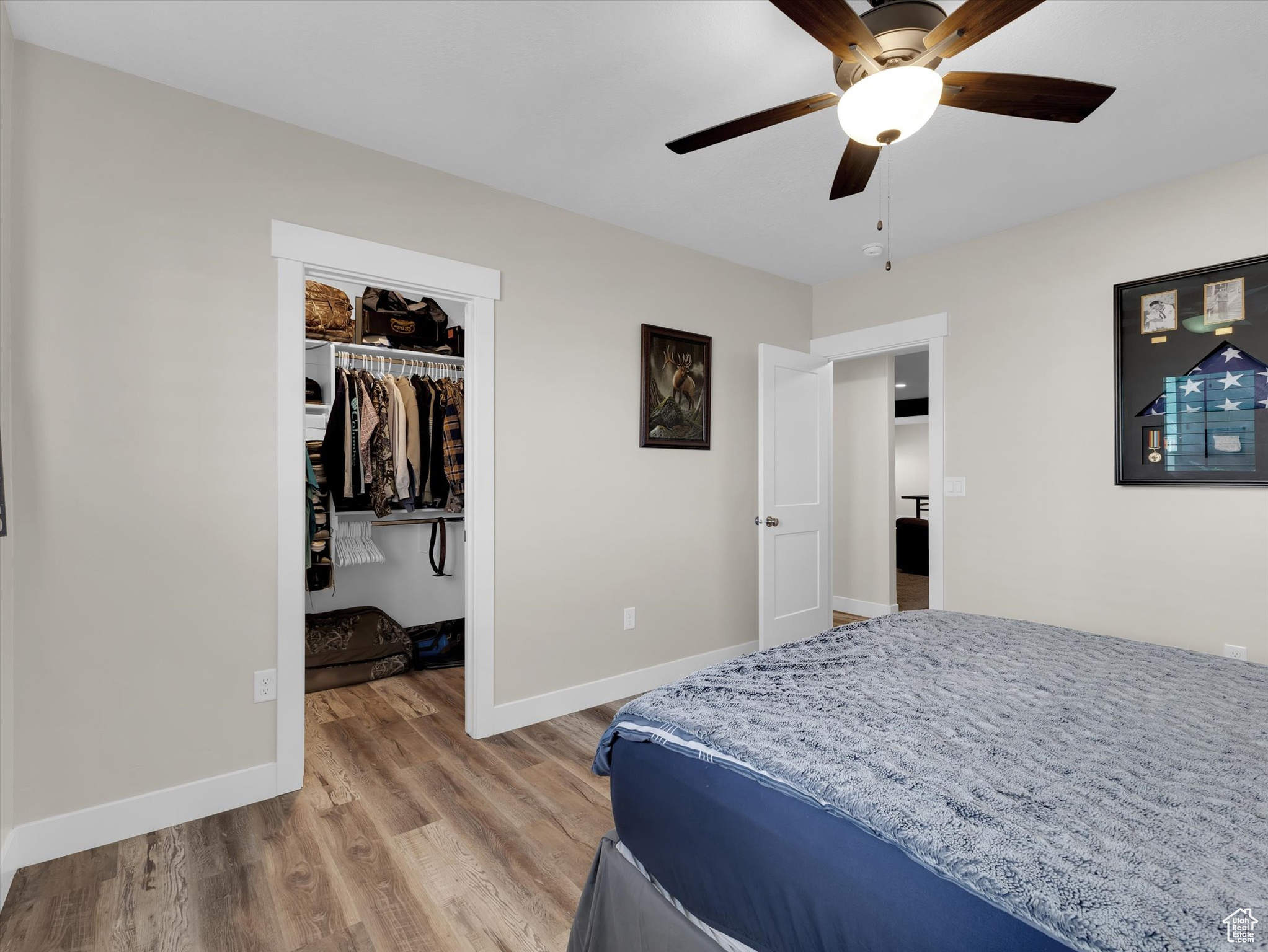 Bedroom #4 with a walk-in closet, ceiling fan, and light hardwood / wood-style floors