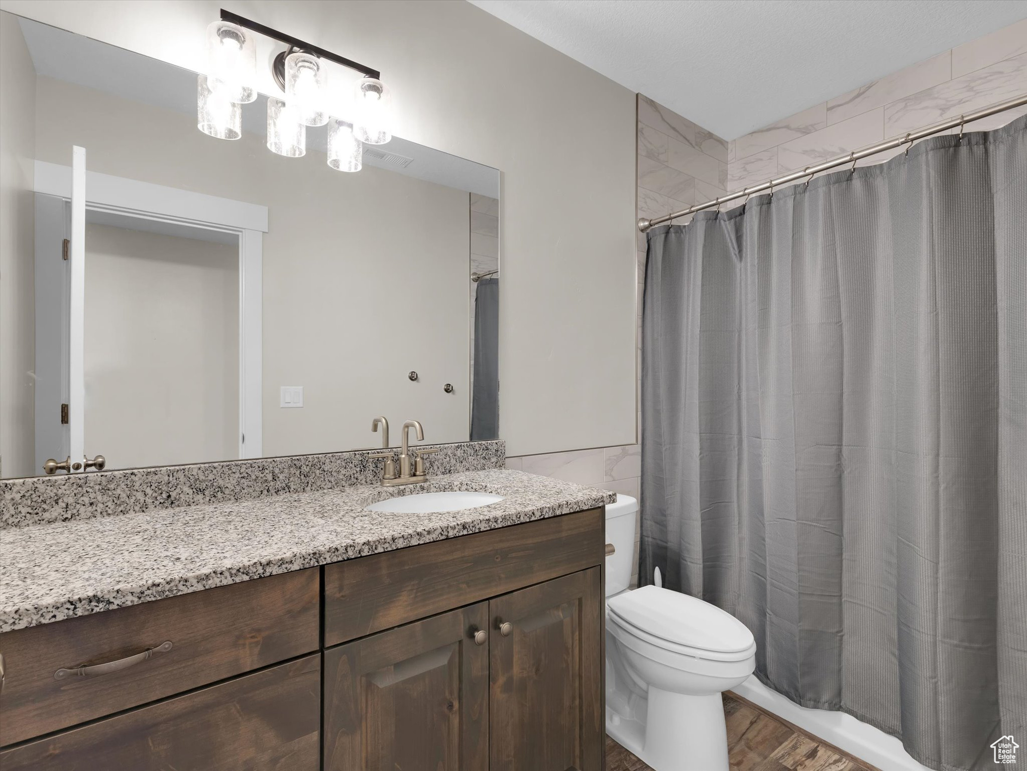 Bathroom featuring hardwood / wood-style floors, vanity, granite counter tops and toilet