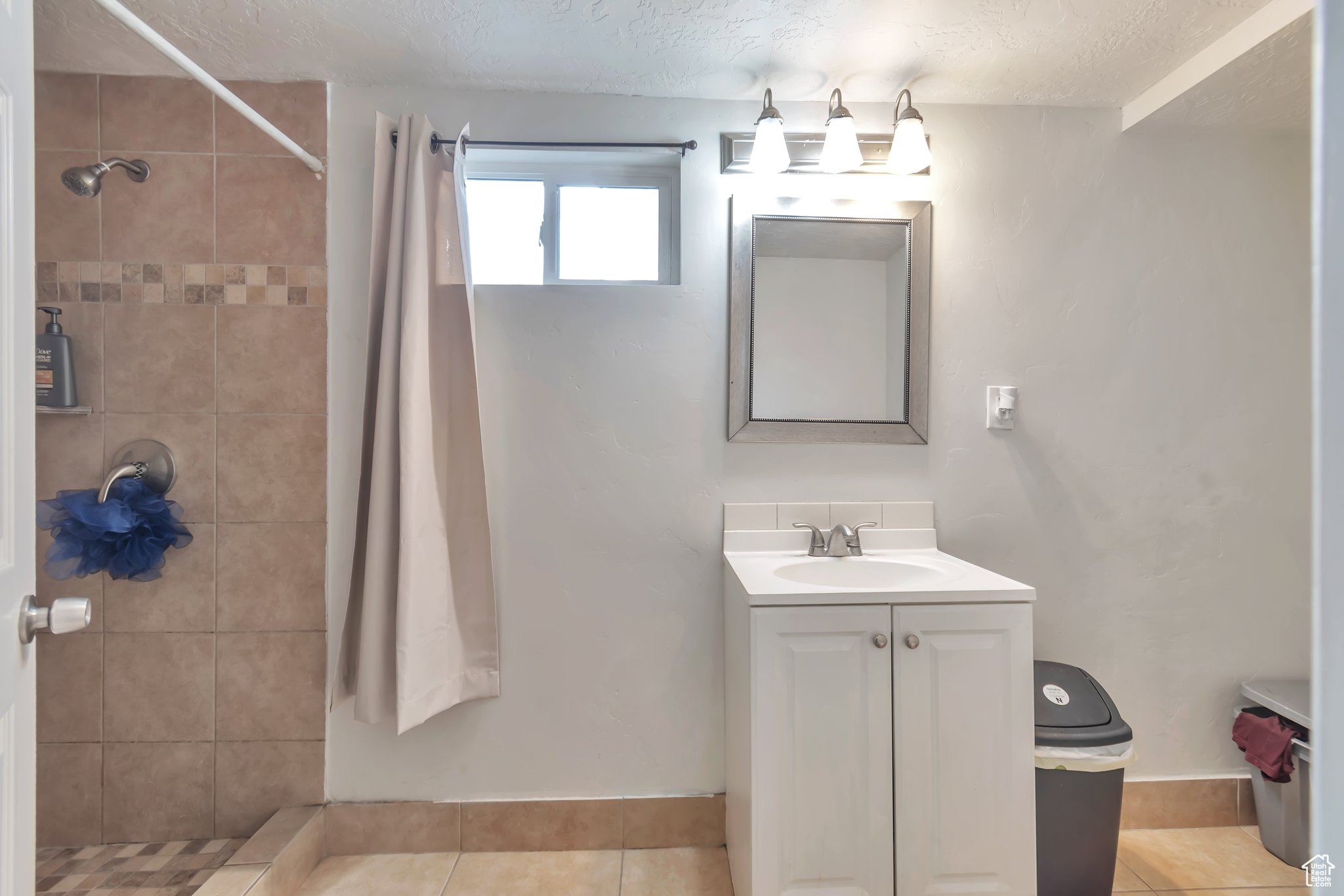 Bathroom featuring vanity with extensive cabinet space, tile floors, walk in shower, and a textured ceiling