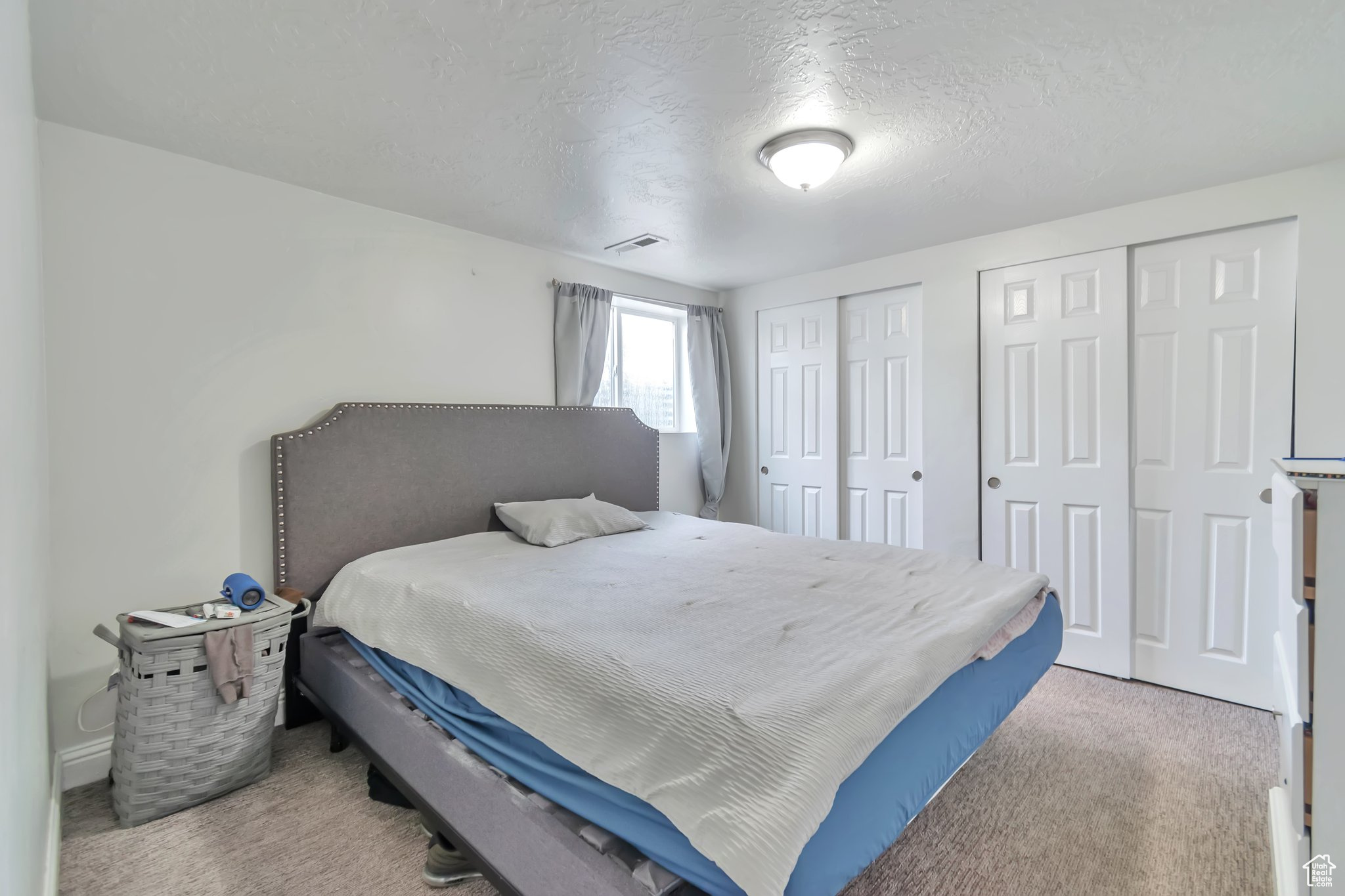 Bedroom featuring light colored carpet, a textured ceiling, and multiple closets