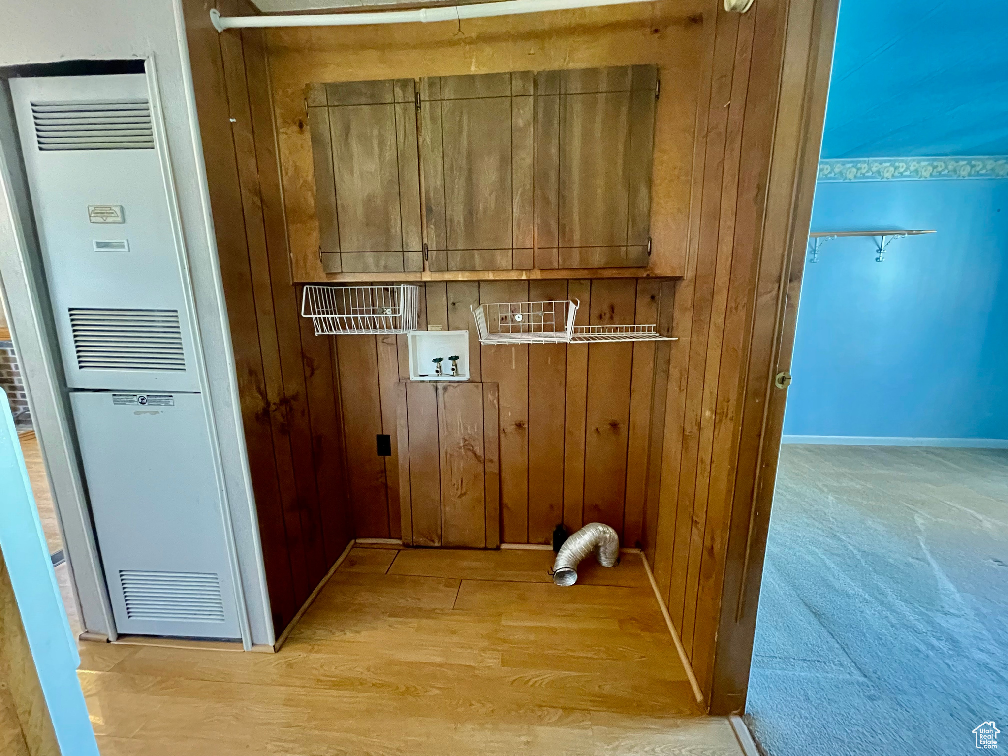 Washroom with hookup for a washing machine, wood walls, and light hardwood / wood-style floors