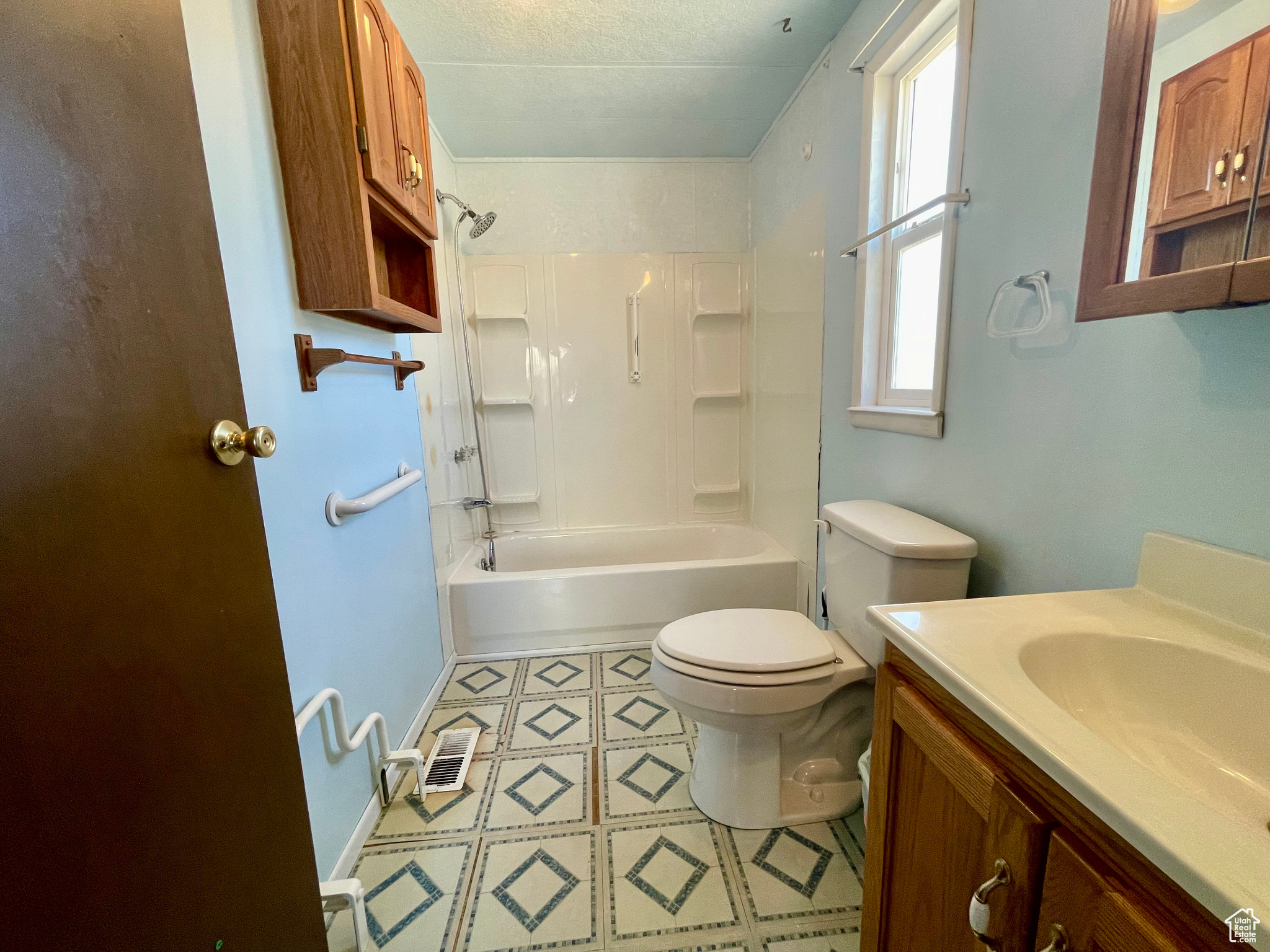 Full bathroom featuring vanity, tile flooring, shower / bath combination, toilet, and a textured ceiling
