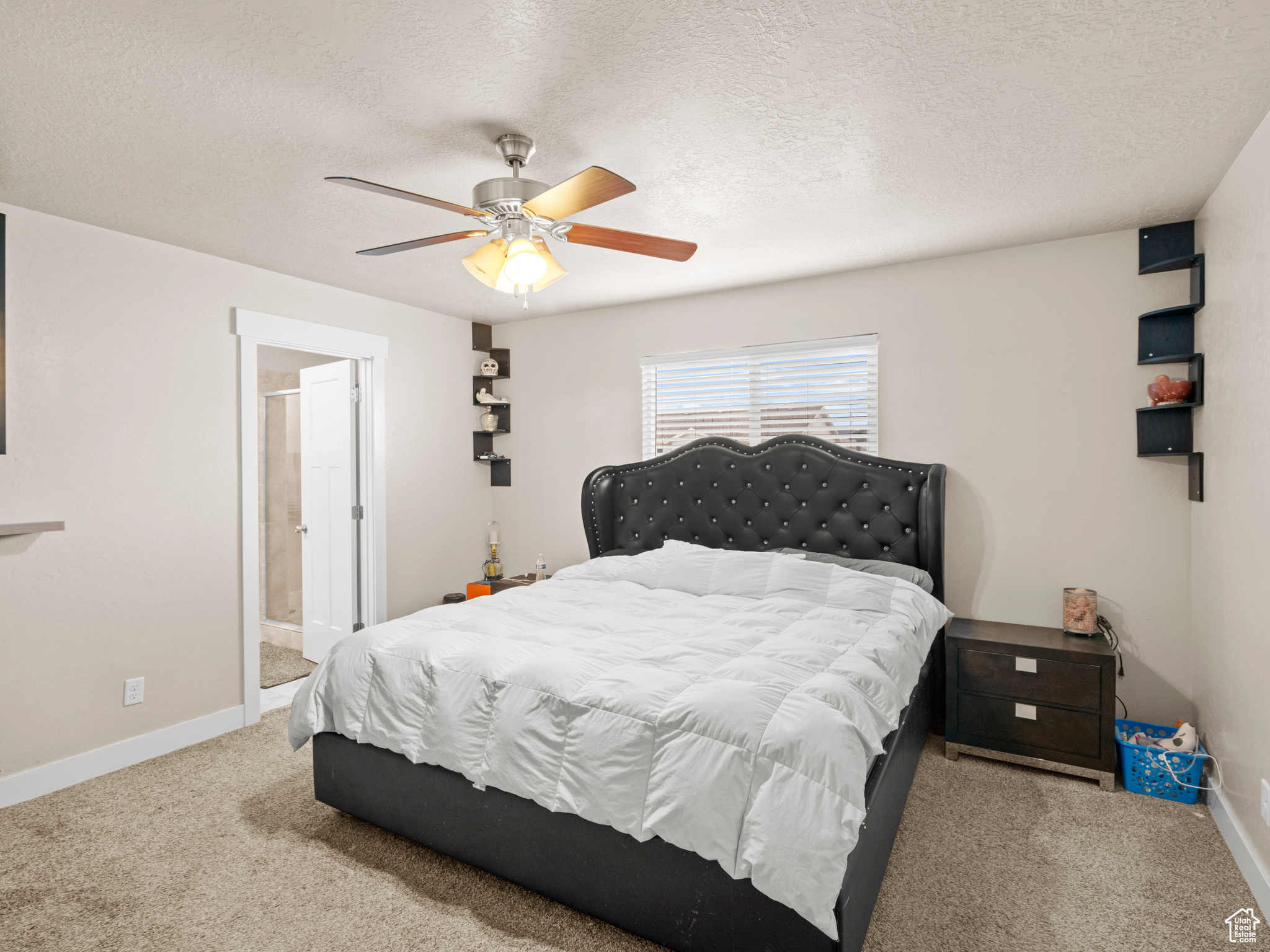 Carpeted bedroom featuring ceiling fan, a textured ceiling, and ensuite bathroom