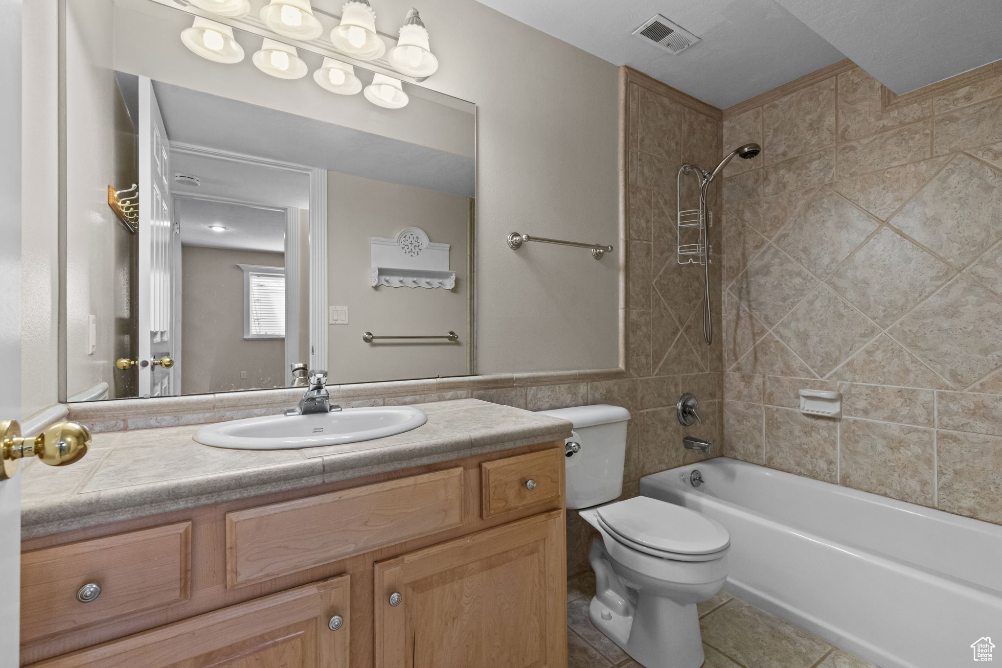 Full bathroom with tiled shower / bath, toilet, tile floors, and vanity