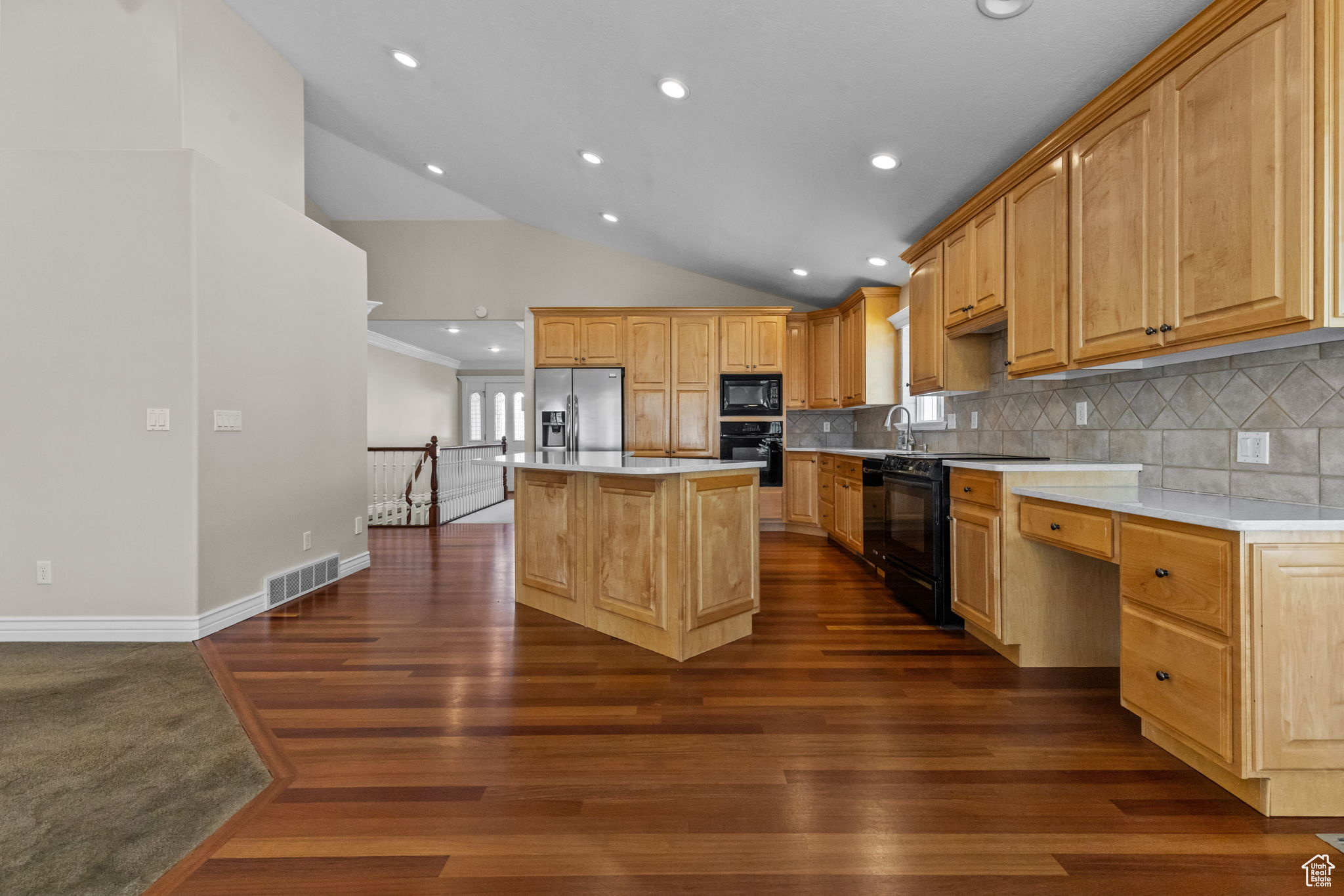Kitchen featuring a kitchen island, backsplash, black appliances, sink, and dark hardwood / wood-style flooring