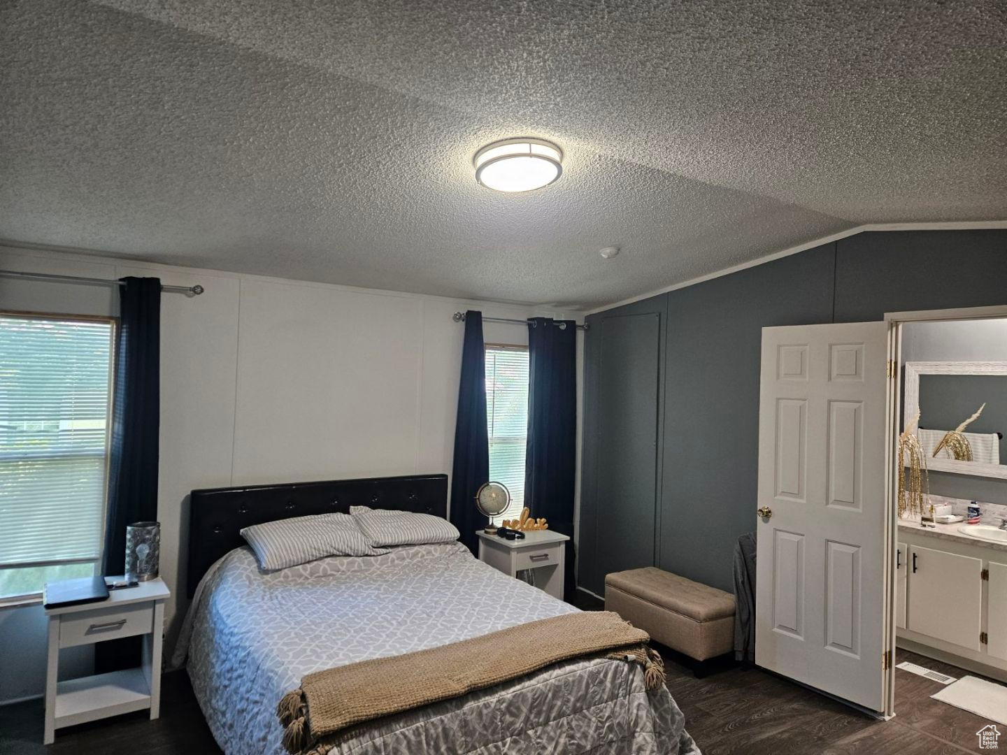 Bedroom featuring dark hardwood / wood-style floors, lofted ceiling, and a textured ceiling