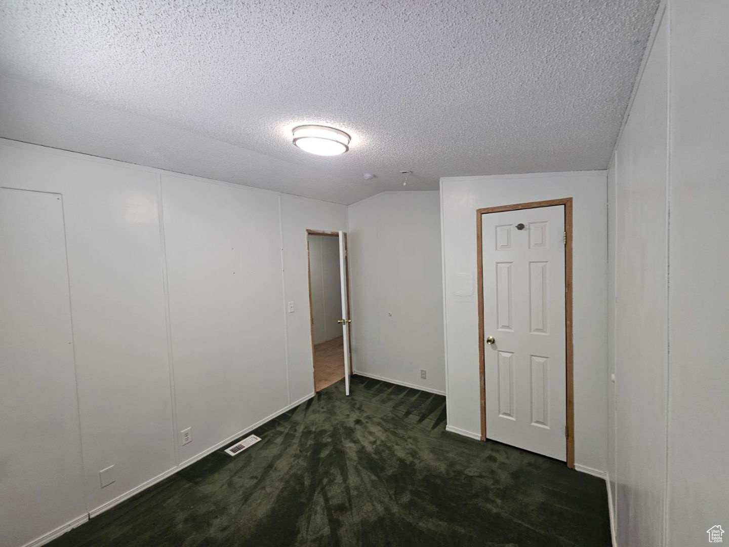 Carpeted spare room featuring a textured ceiling