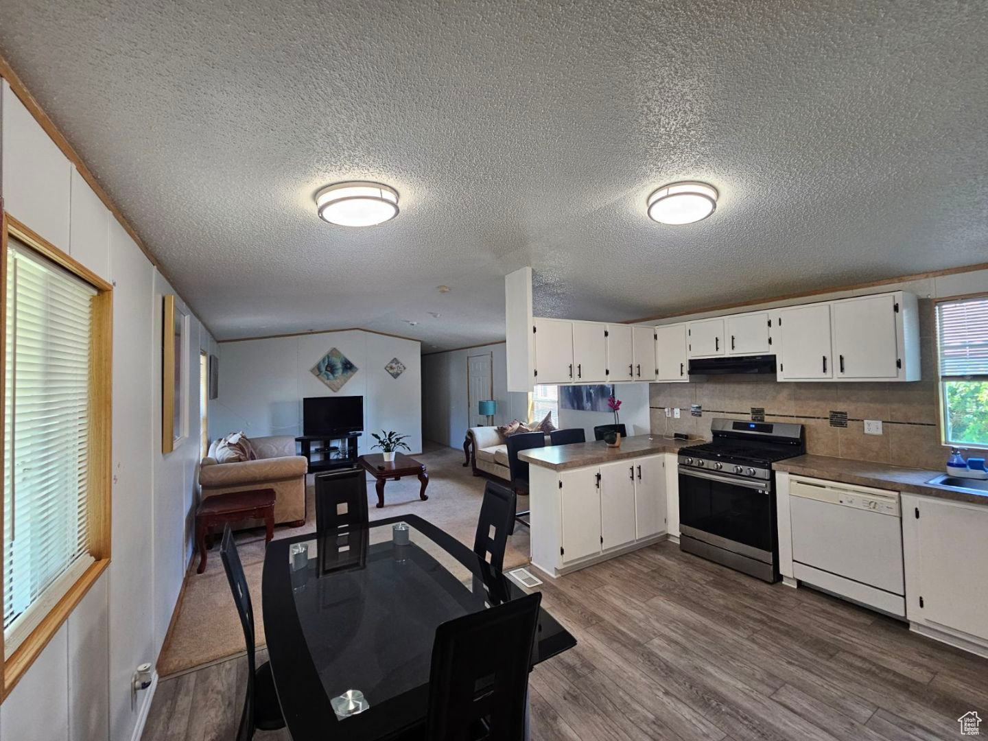 Kitchen featuring white cabinets, gas stove, white dishwasher, and wood-type flooring