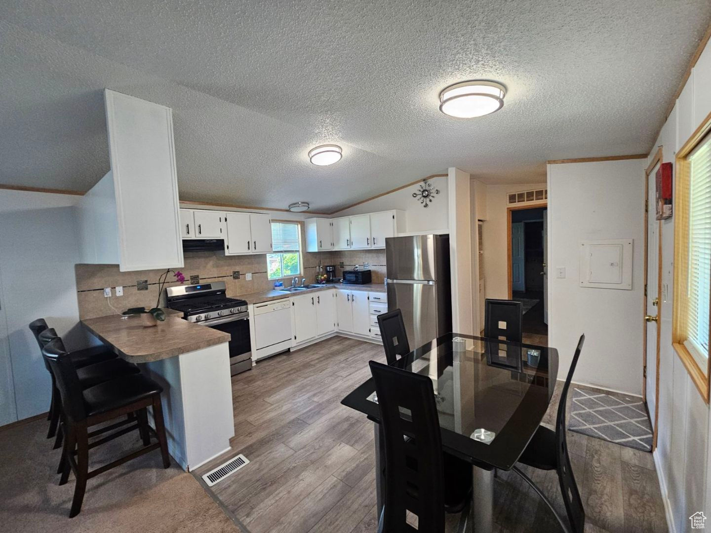 Dining room featuring sink, a textured ceiling, dark hardwood / wood-style flooring, and lofted ceiling