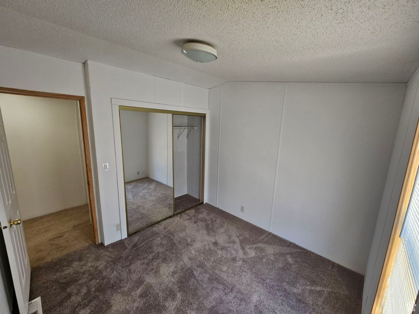 Unfurnished bedroom featuring a closet, a textured ceiling, and dark carpet