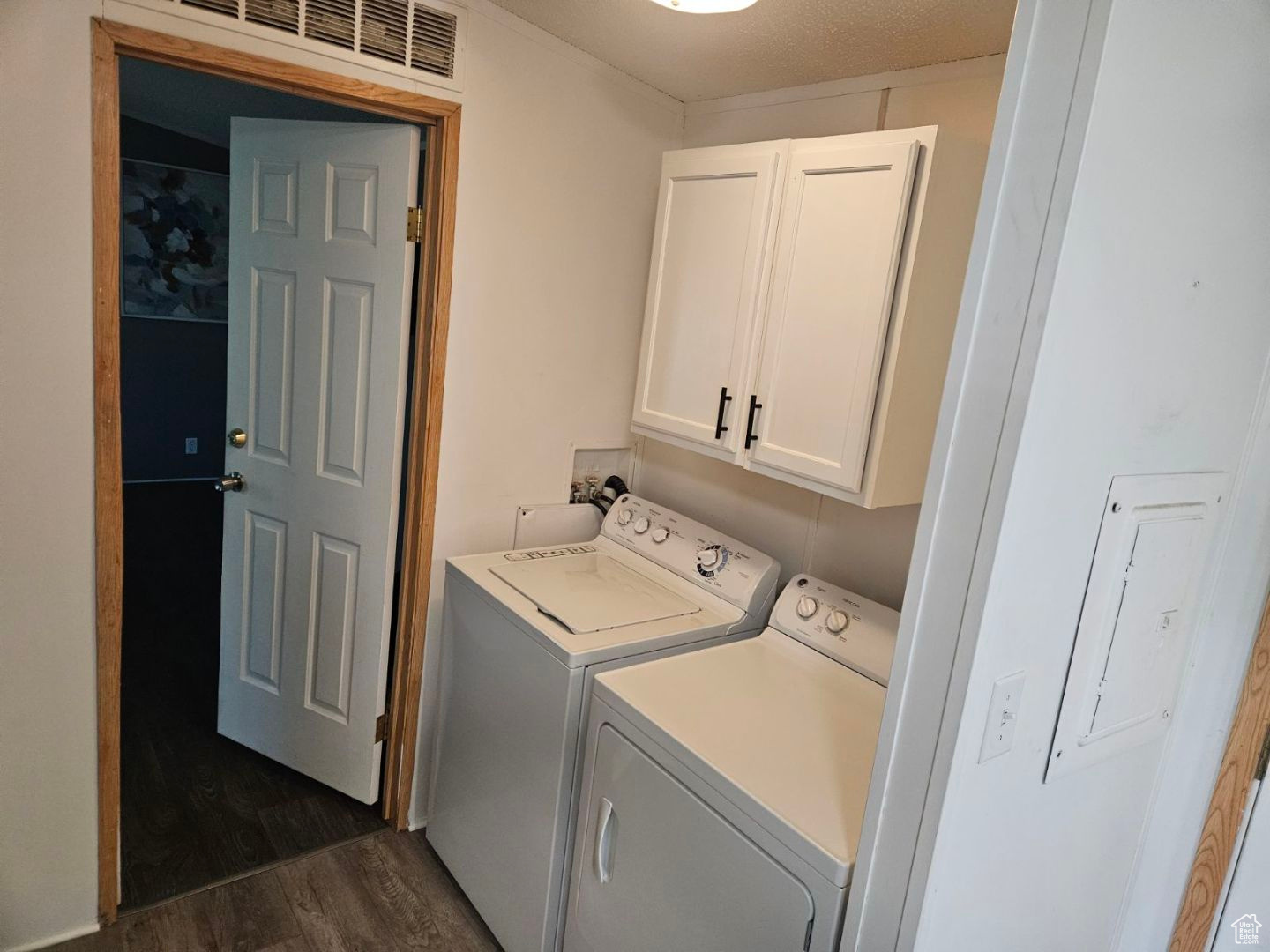 Washroom featuring cabinets, washing machine and dryer, and dark wood-type flooring