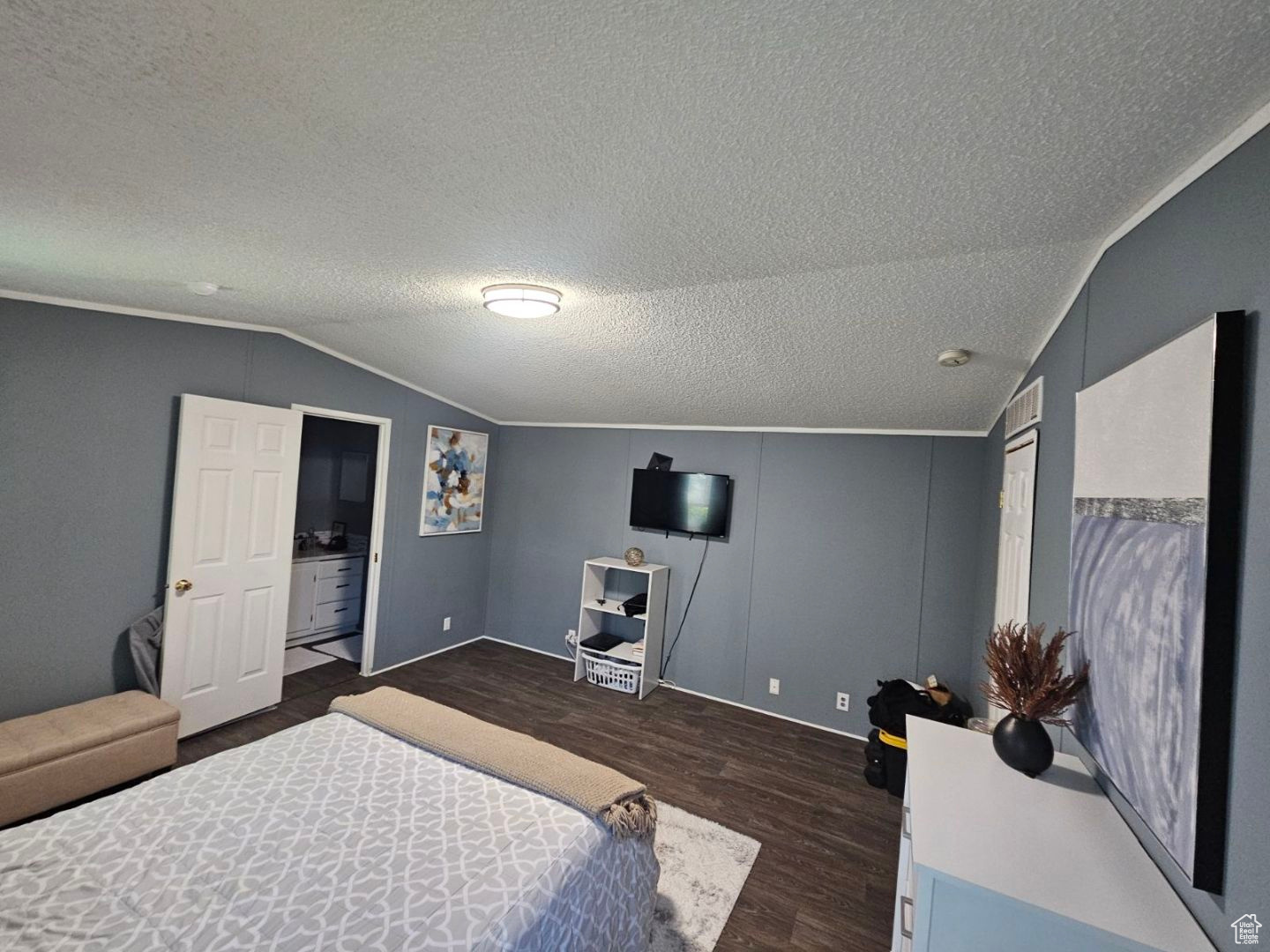 Bedroom with dark wood-type flooring, a textured ceiling, and vaulted ceiling