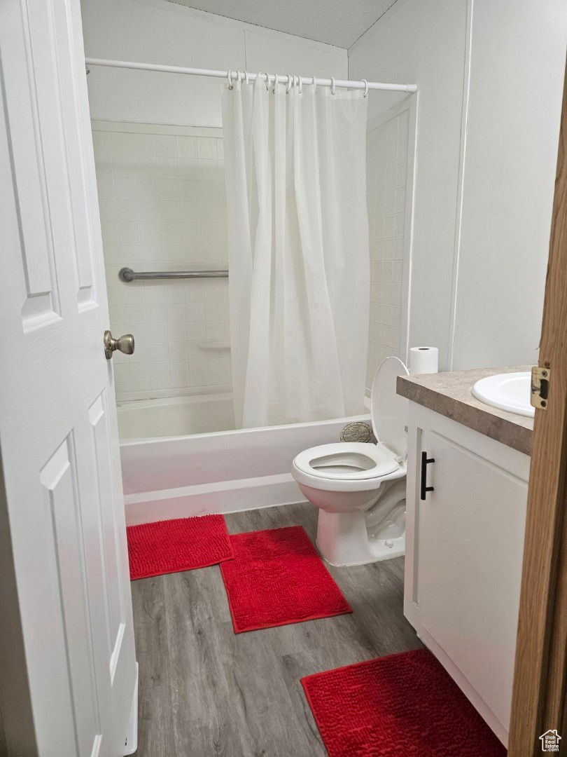 Full bathroom with shower / tub combo, toilet, hardwood / wood-style floors, and vanity