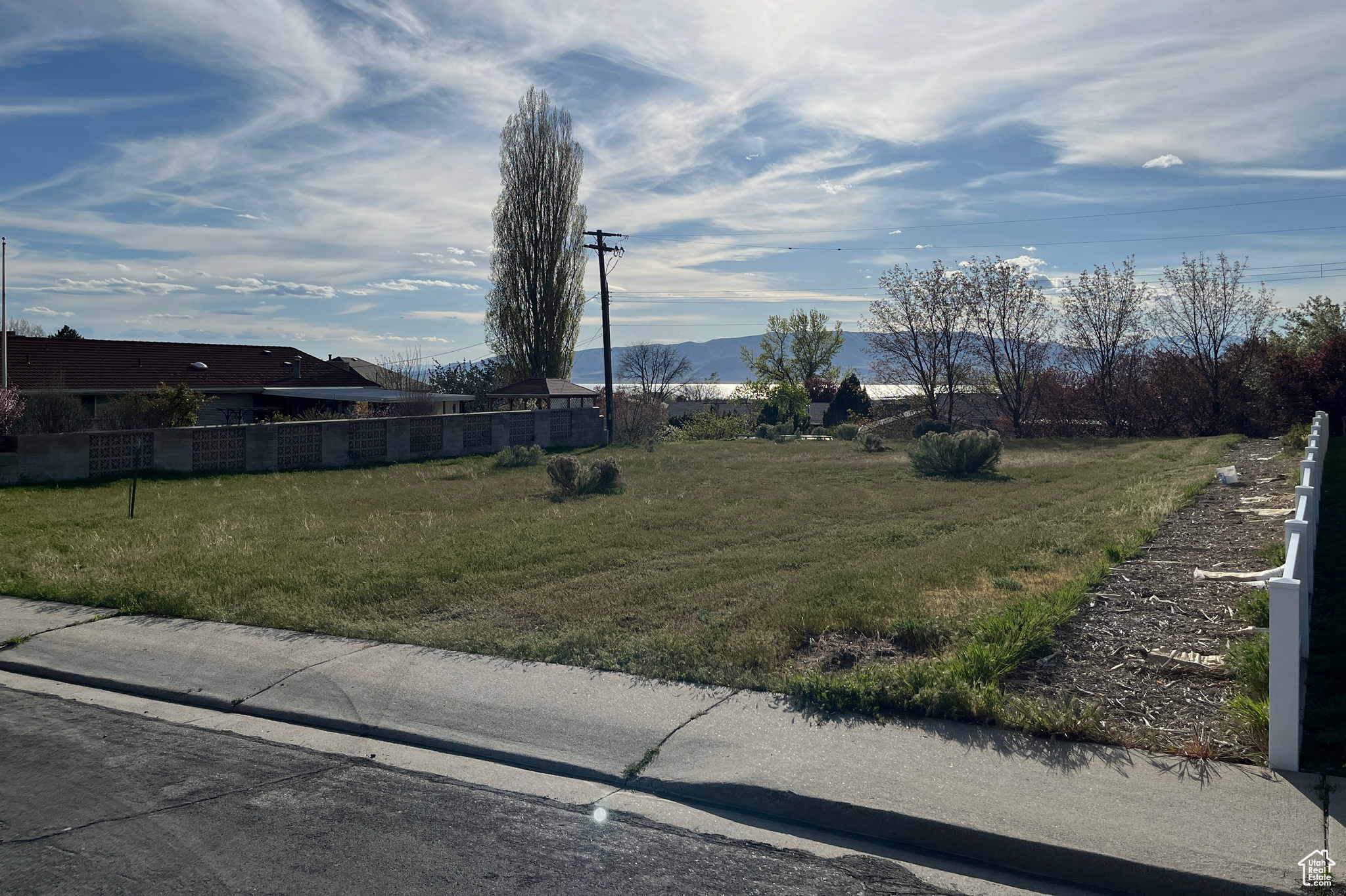 Street view of yard from the North East corner and looking West. Features a large flat building lot with views of Utah Lake and mountains.