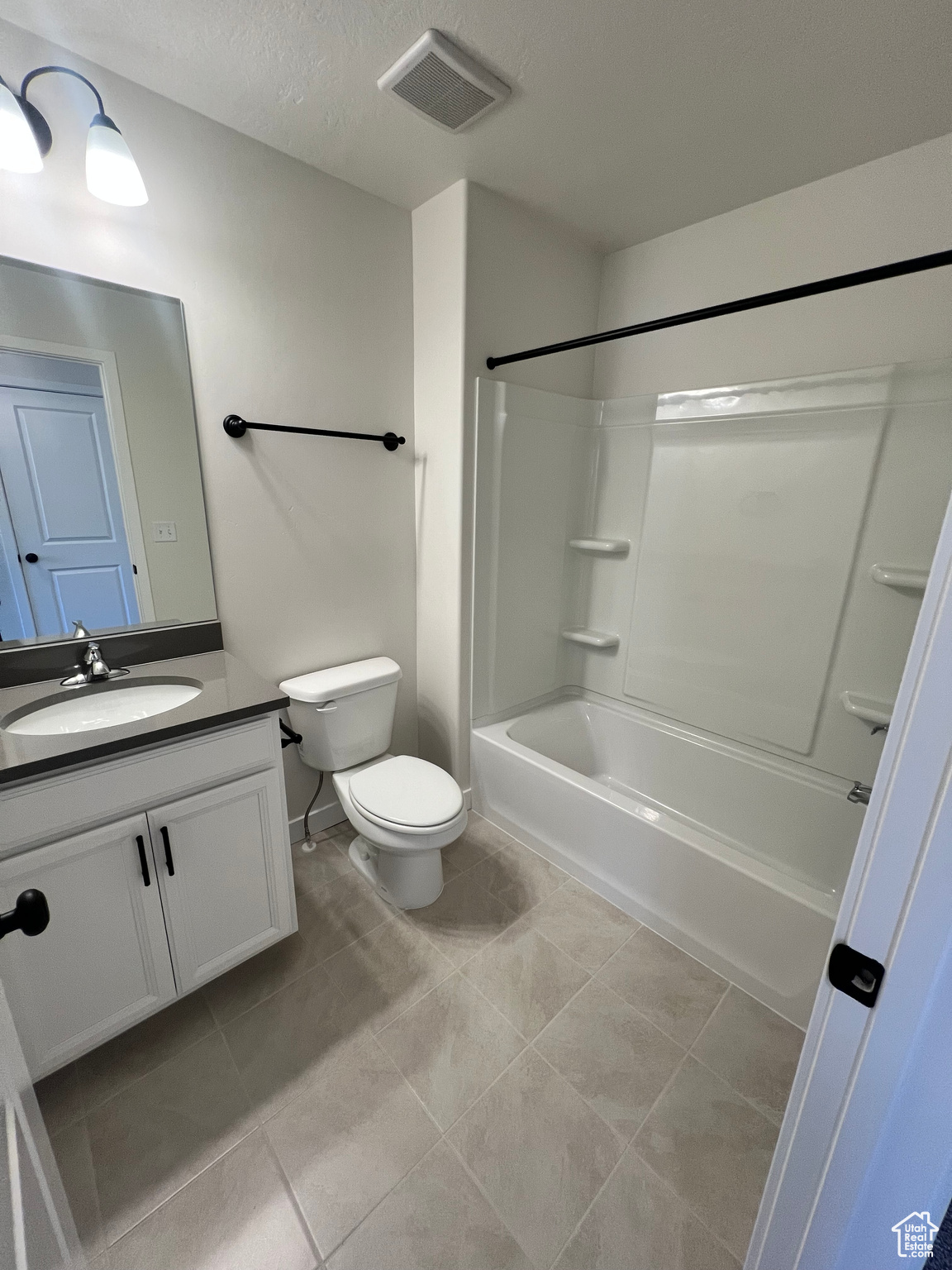 Full bathroom featuring large vanity, shower / bathtub combination, toilet, a textured ceiling, and tile floors