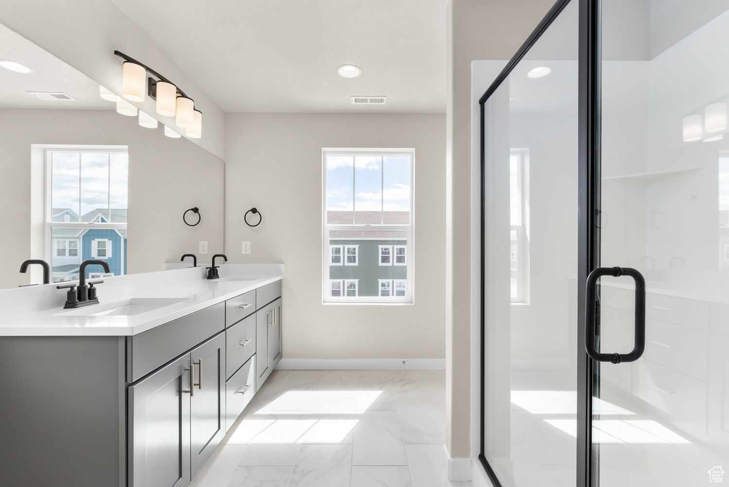 Bathroom with tile flooring, double sink vanity, and a shower with shower door