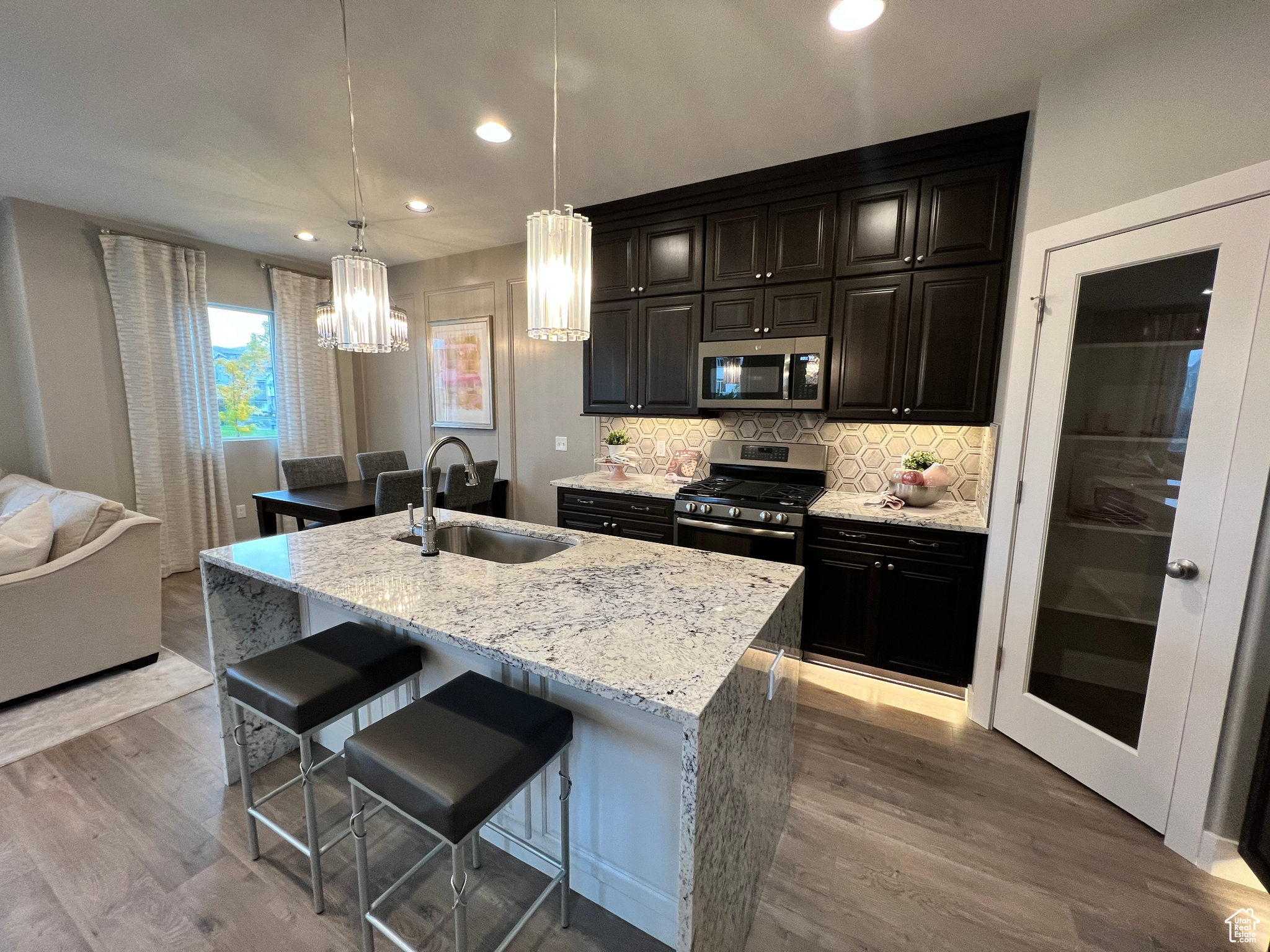 Kitchen featuring stainless steel appliances, hardwood / wood-style flooring, an island with sink, a kitchen breakfast bar, and sink