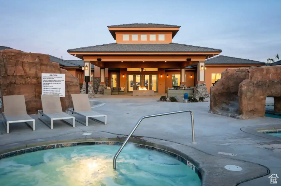 Back house at dusk with a patio and a pool with hot tub