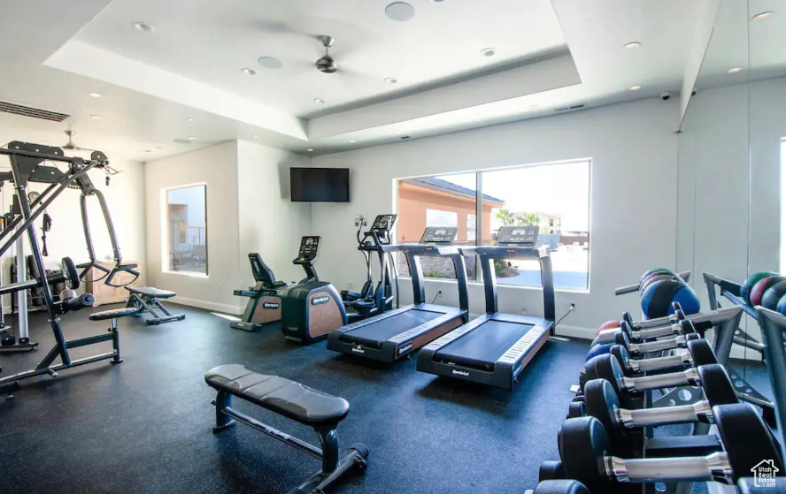 Gym with a raised ceiling and ceiling fan