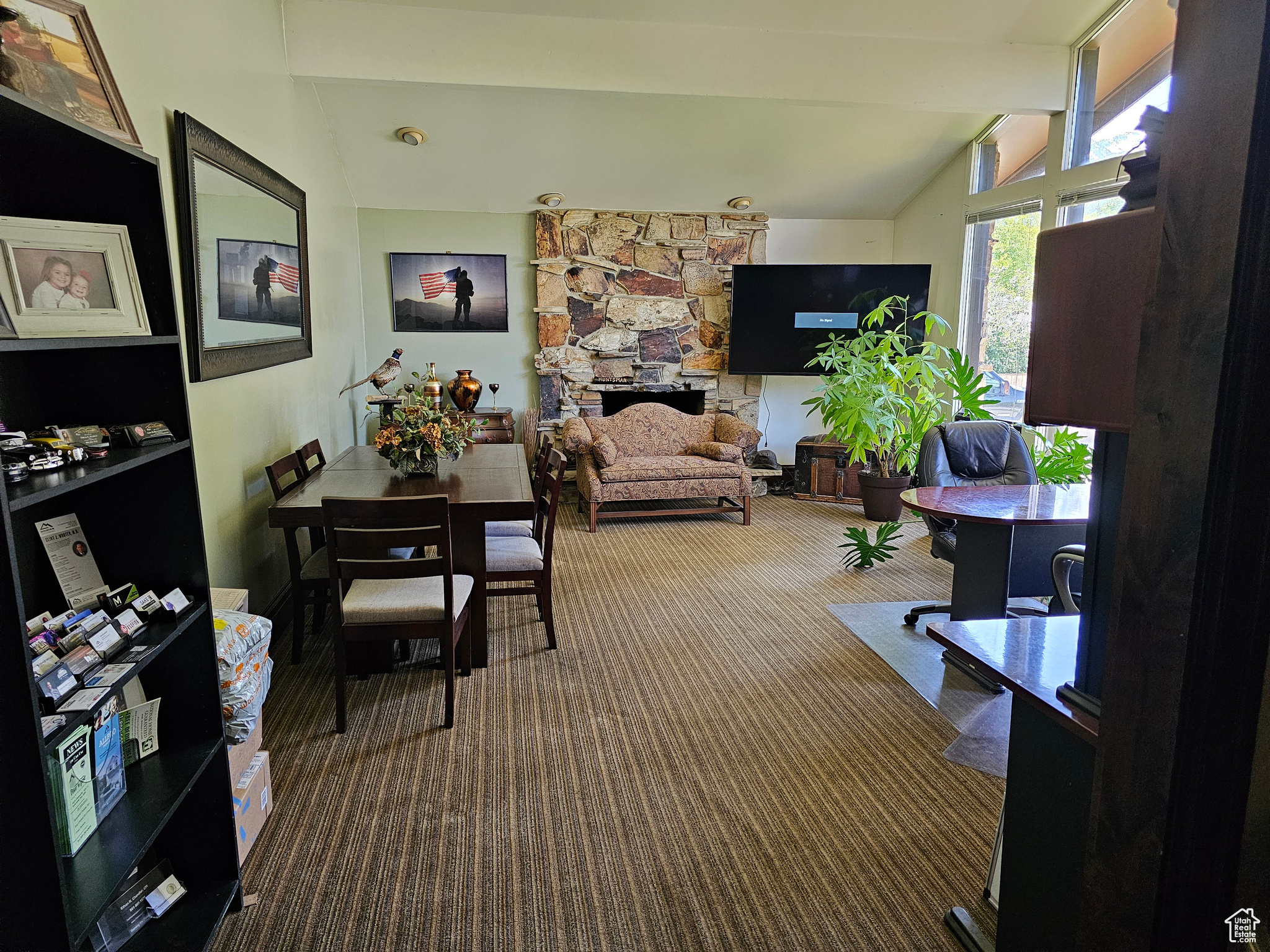 Living room featuring vaulted ceiling with beams, a stone fireplace, and carpet floors