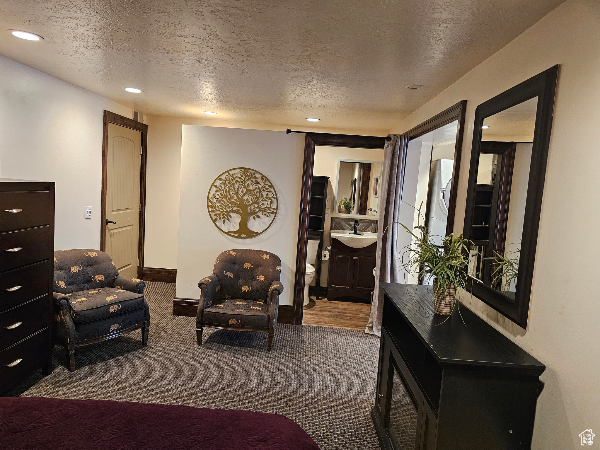 CASISTA-Carpeted bedroom with connected bathroom, sink, and a textured ceiling