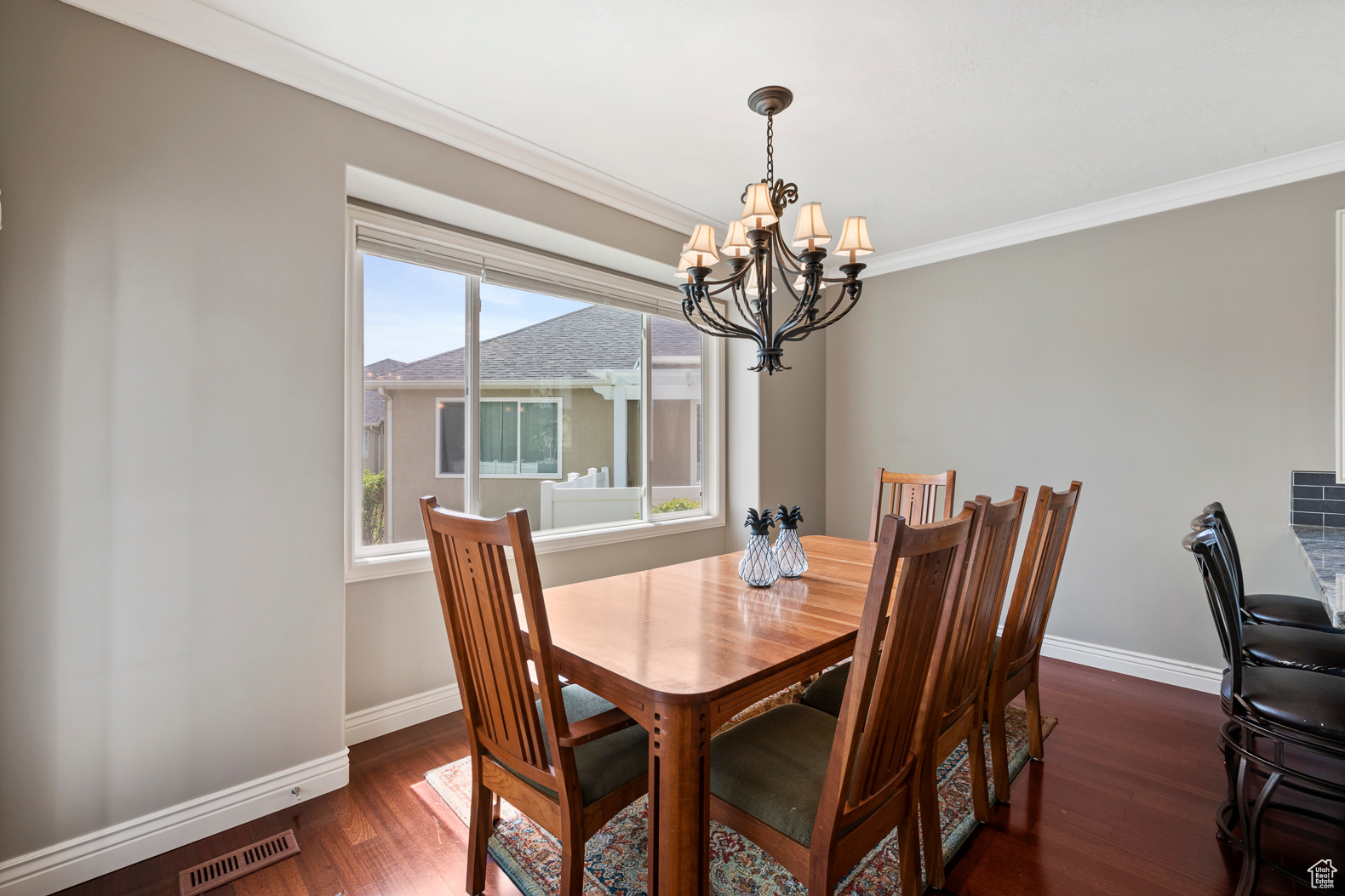 Dining space with an inviting chandelier, dark wood-type flooring, and crown molding