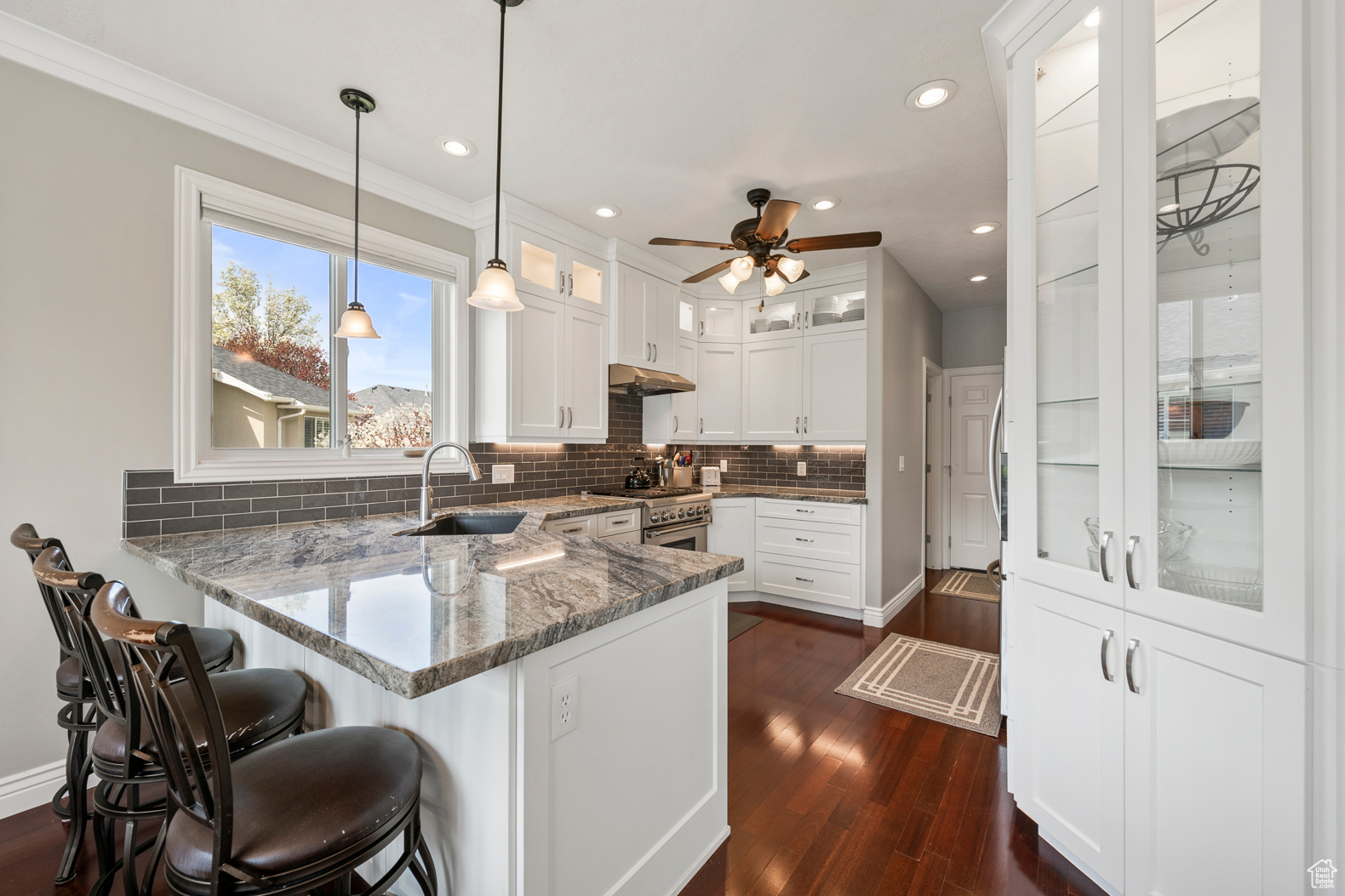 Kitchen featuring ceiling fan, white cabinets, sink, dark wood-type flooring, and kitchen peninsula
