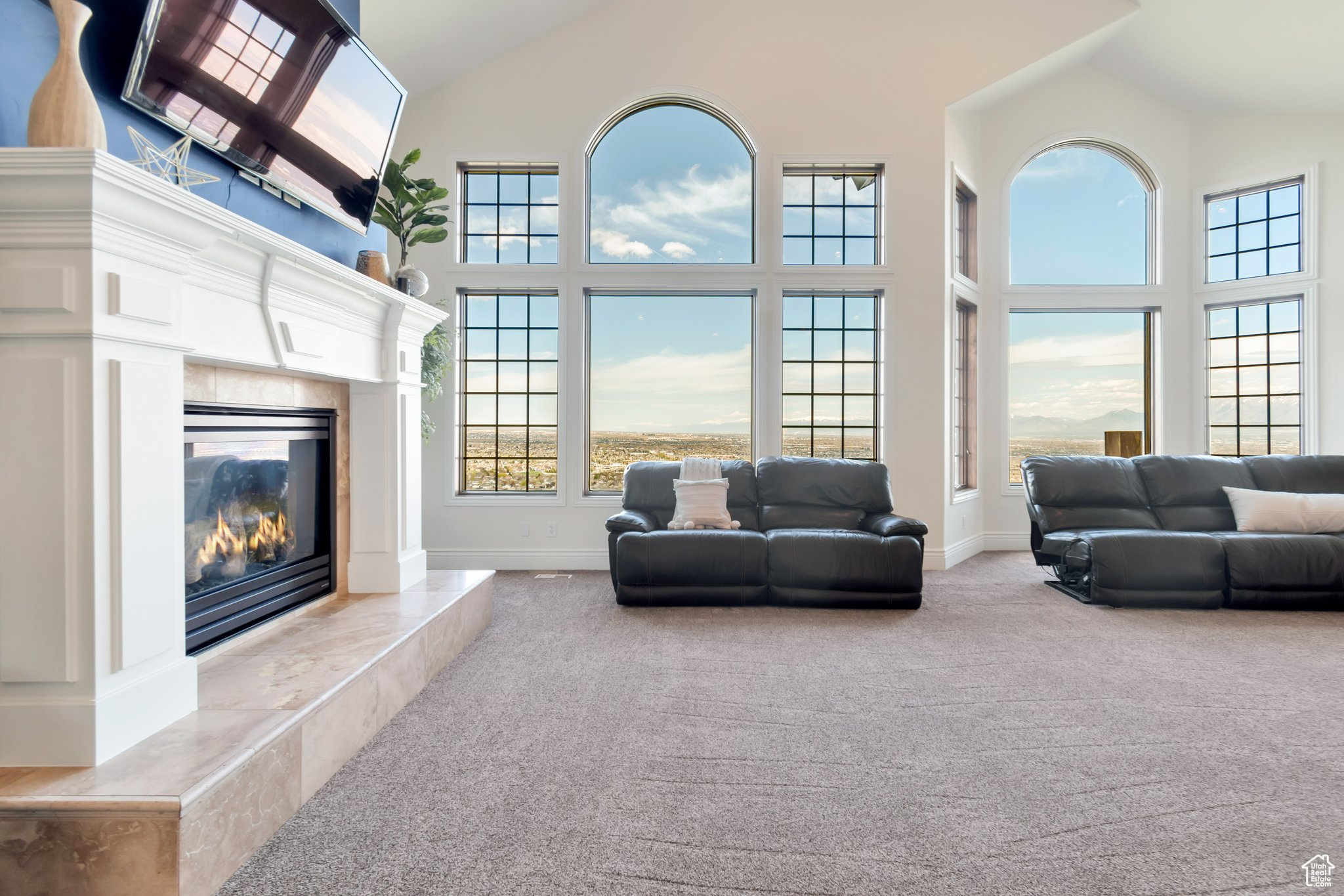 Living room featuring light colored carpet, high vaulted ceiling, and a fireplace
