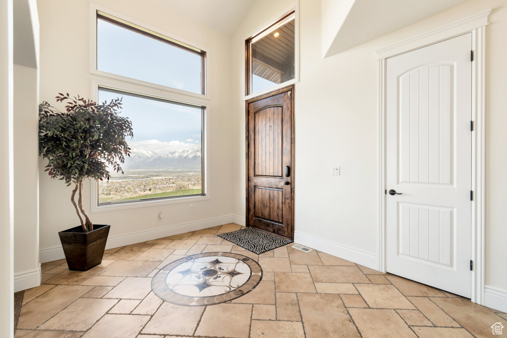 Entryway with vaulted ceiling, a mountain view, and light tile flooring