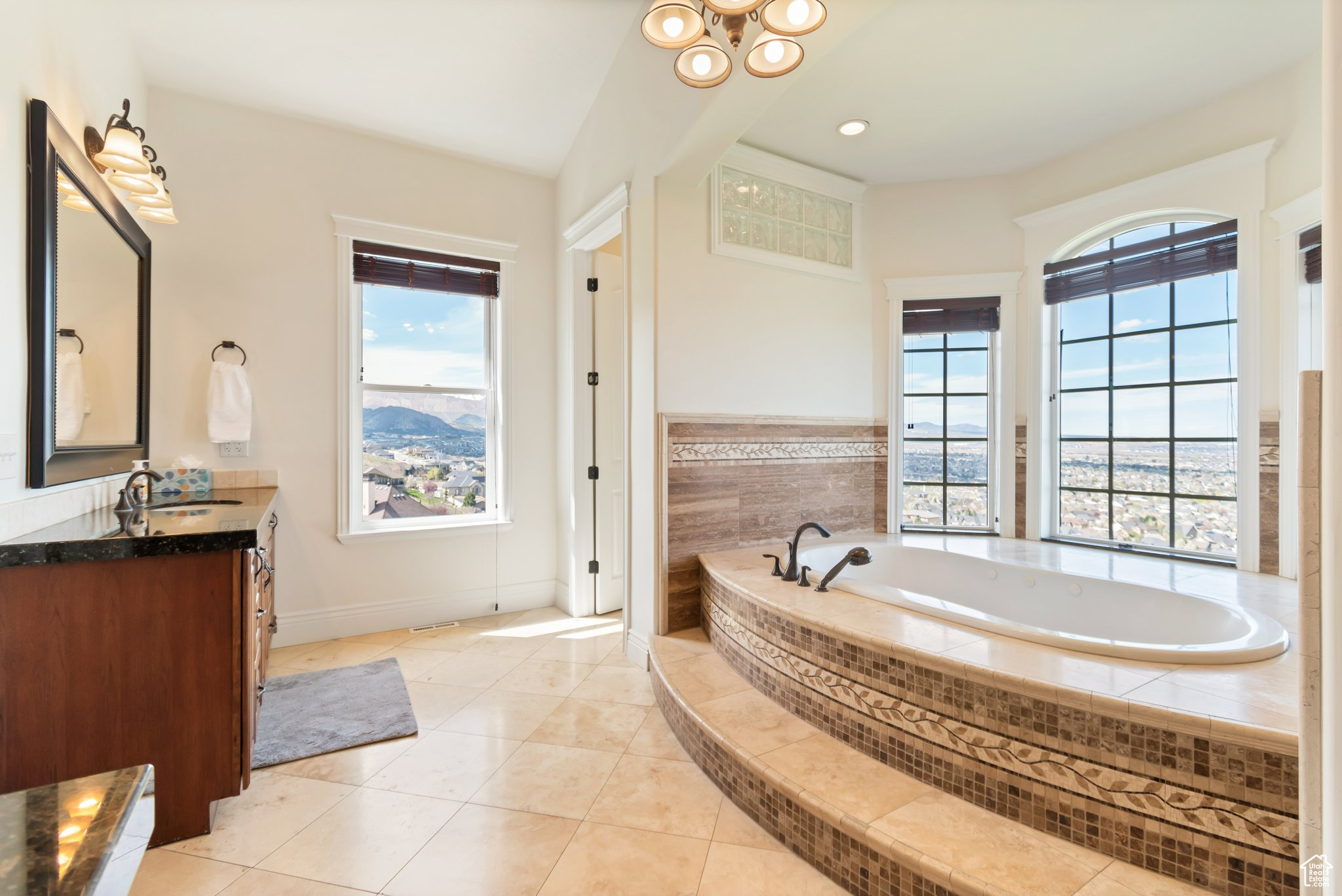 Bathroom featuring tile flooring, vanity, and tiled bath
