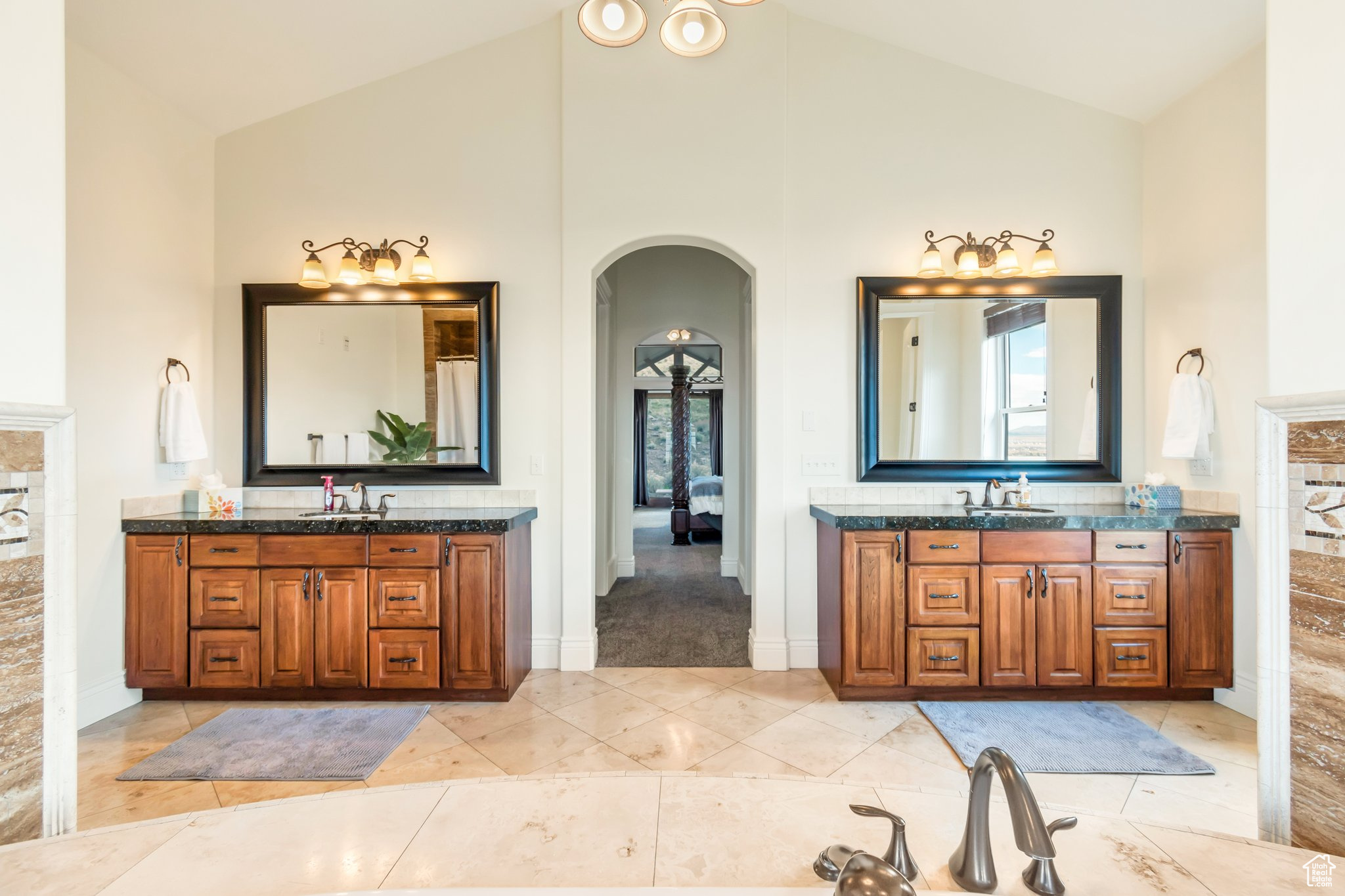 Bathroom featuring high vaulted ceiling, dual bowl vanity, and tile flooring