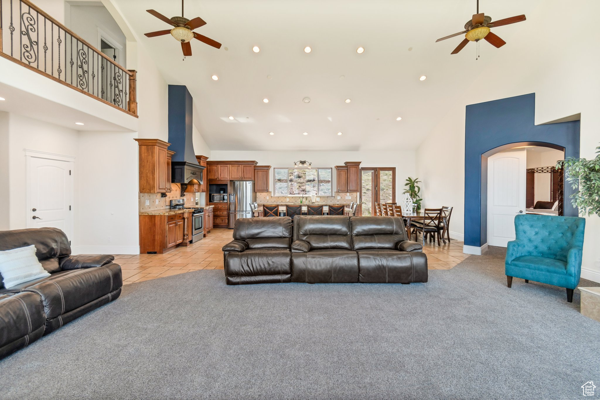 Carpeted living room featuring ceiling fan and high vaulted ceiling