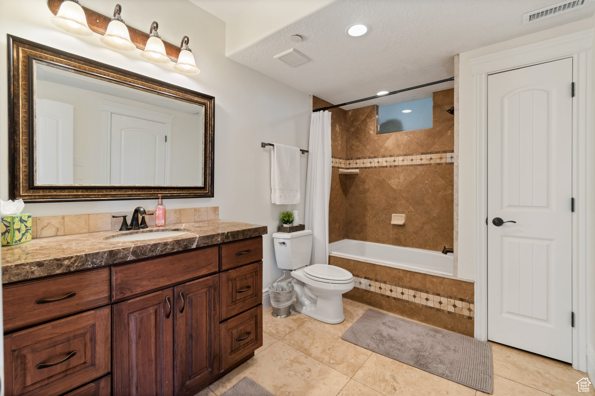Full bathroom featuring shower / bathtub combination with curtain, toilet, vanity with extensive cabinet space, and tile flooring