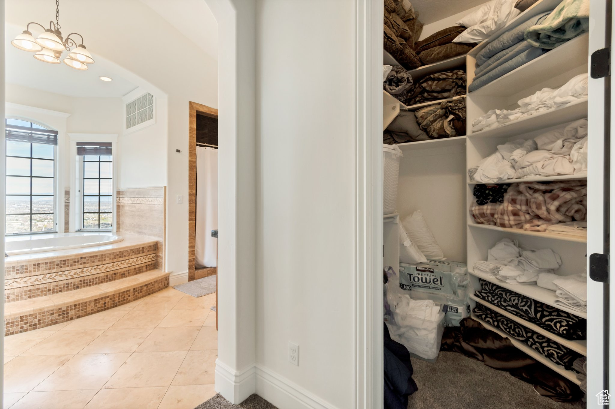 Walk in closet with a chandelier and light tile flooring