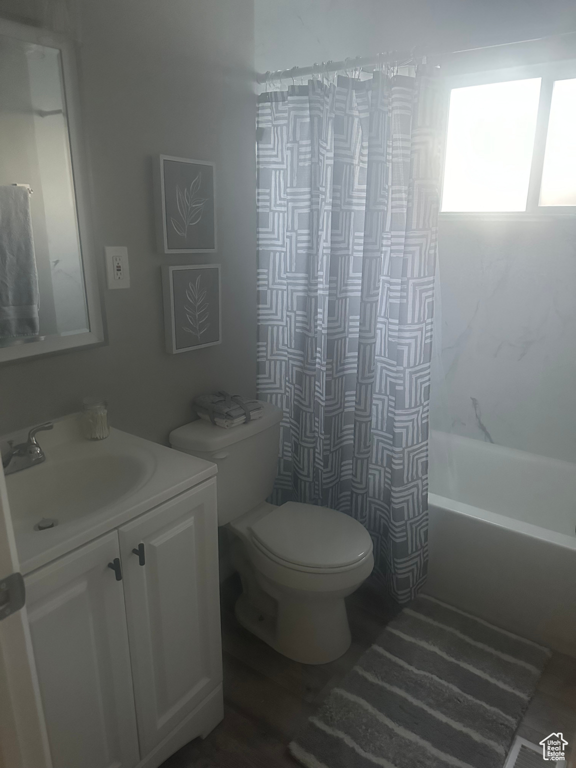 Full bathroom with shower / bath combination with curtain, hardwood / wood-style floors, vanity, and toilet