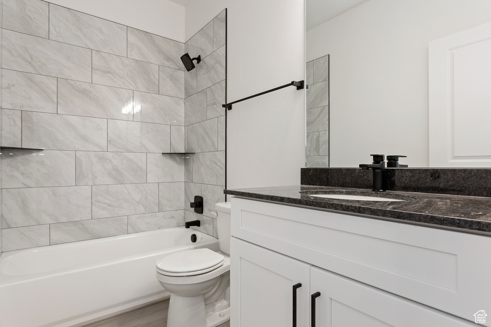 Full bathroom featuring tiled shower / bath, vanity, hardwood / wood-style flooring, and toilet