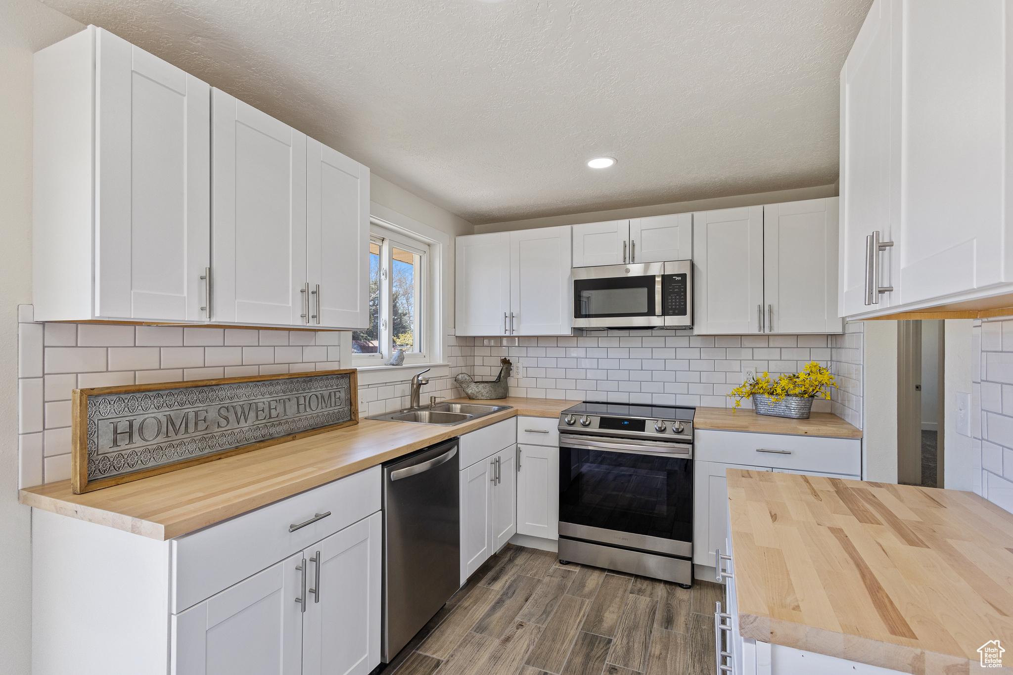 Updated Kitchen featuring tiled backsplash, Stainless appliances , Butcher Block countertops, and tile floors.