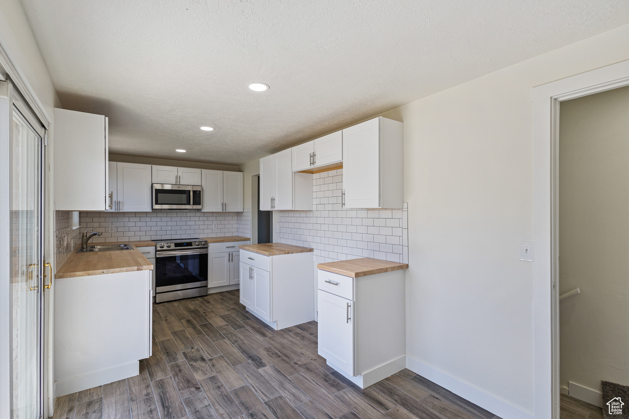 Updated Kitchen featuring tiled backsplash, Stainless appliances , Butcher Block countertops, and tile floors.