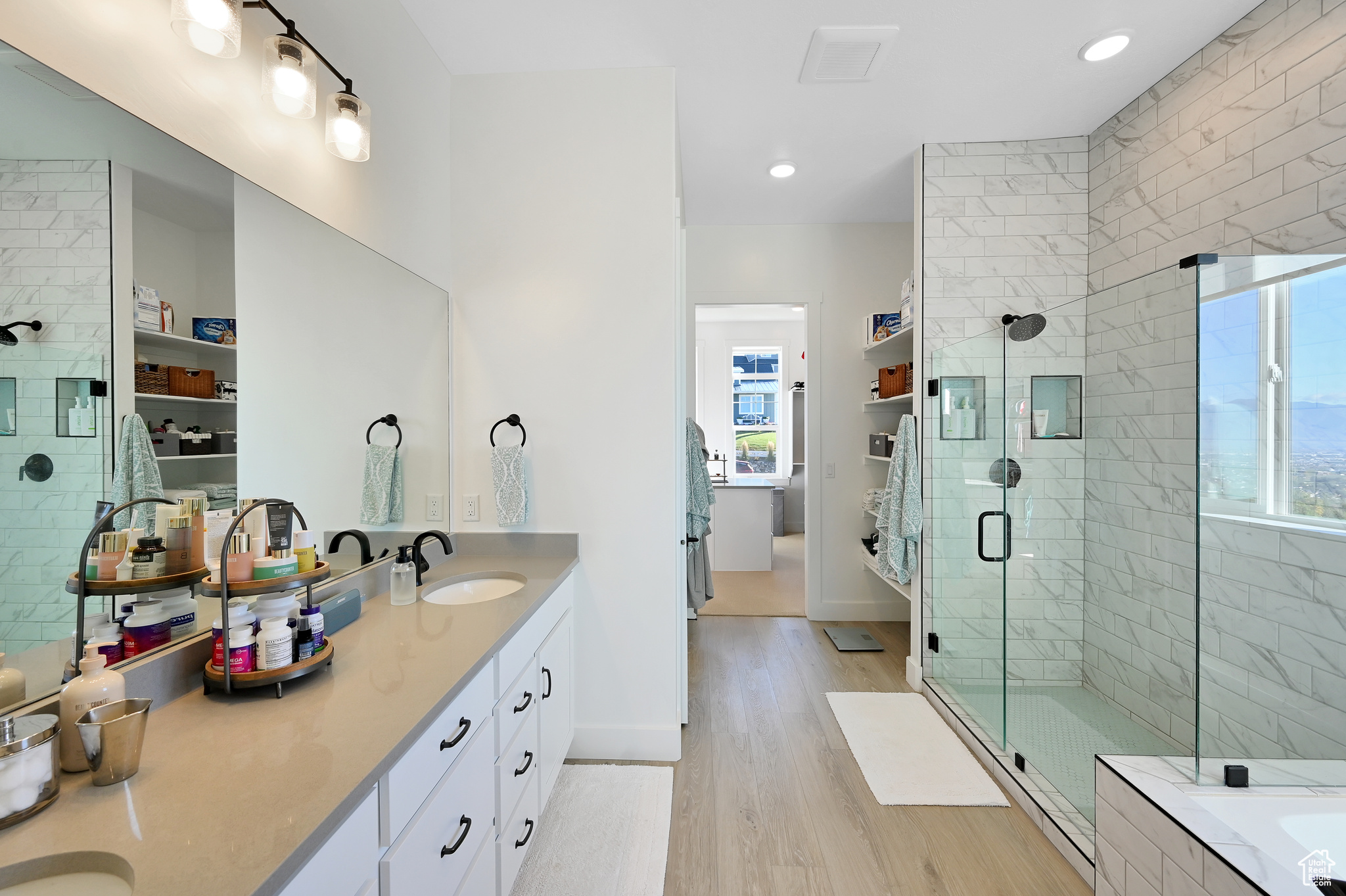 Bathroom with wood-type flooring, plus walk in shower, and double sink vanity