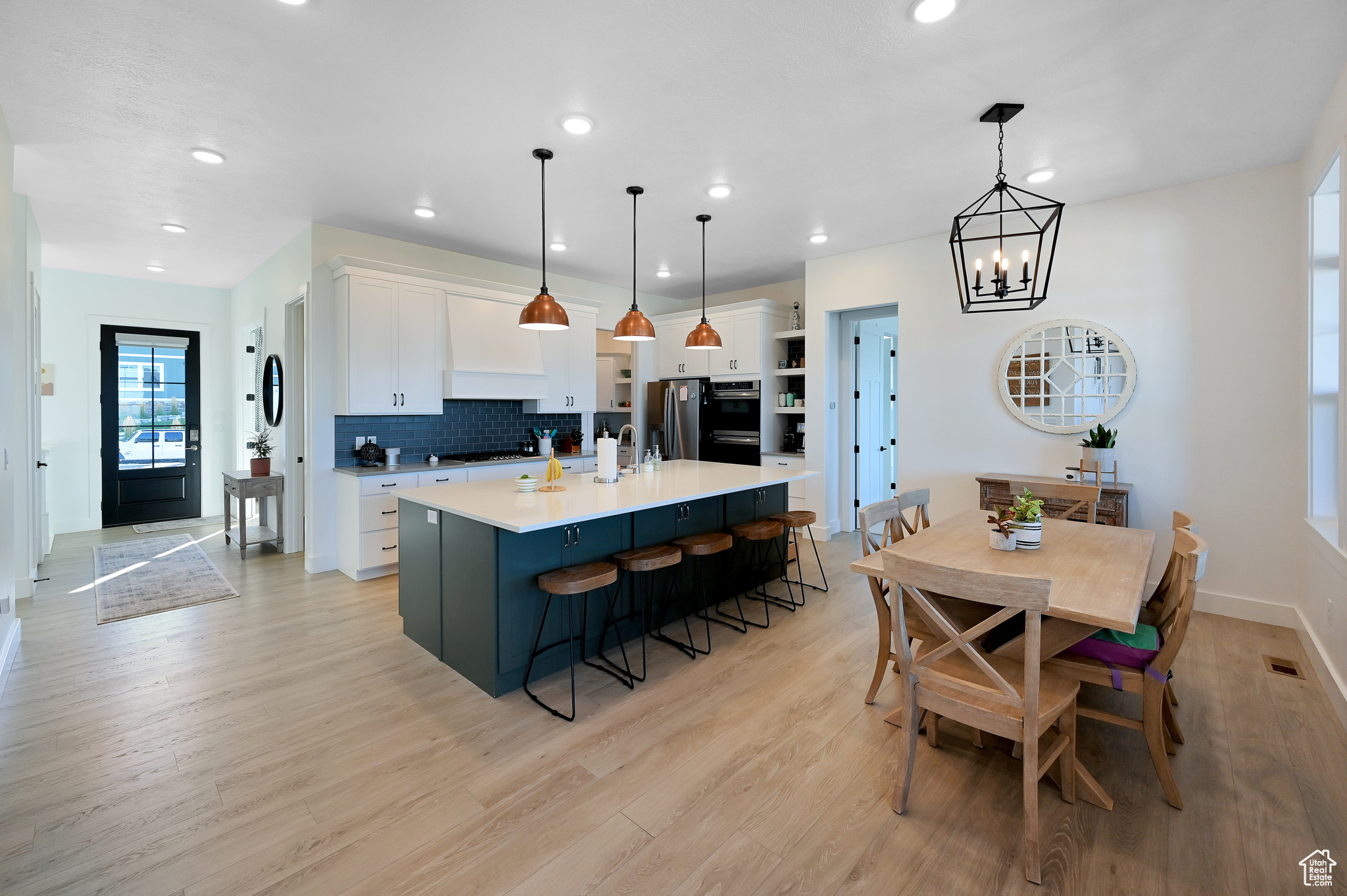 Kitchen with backsplash, light hardwood / wood-style flooring, a kitchen island with sink, and white cabinetry