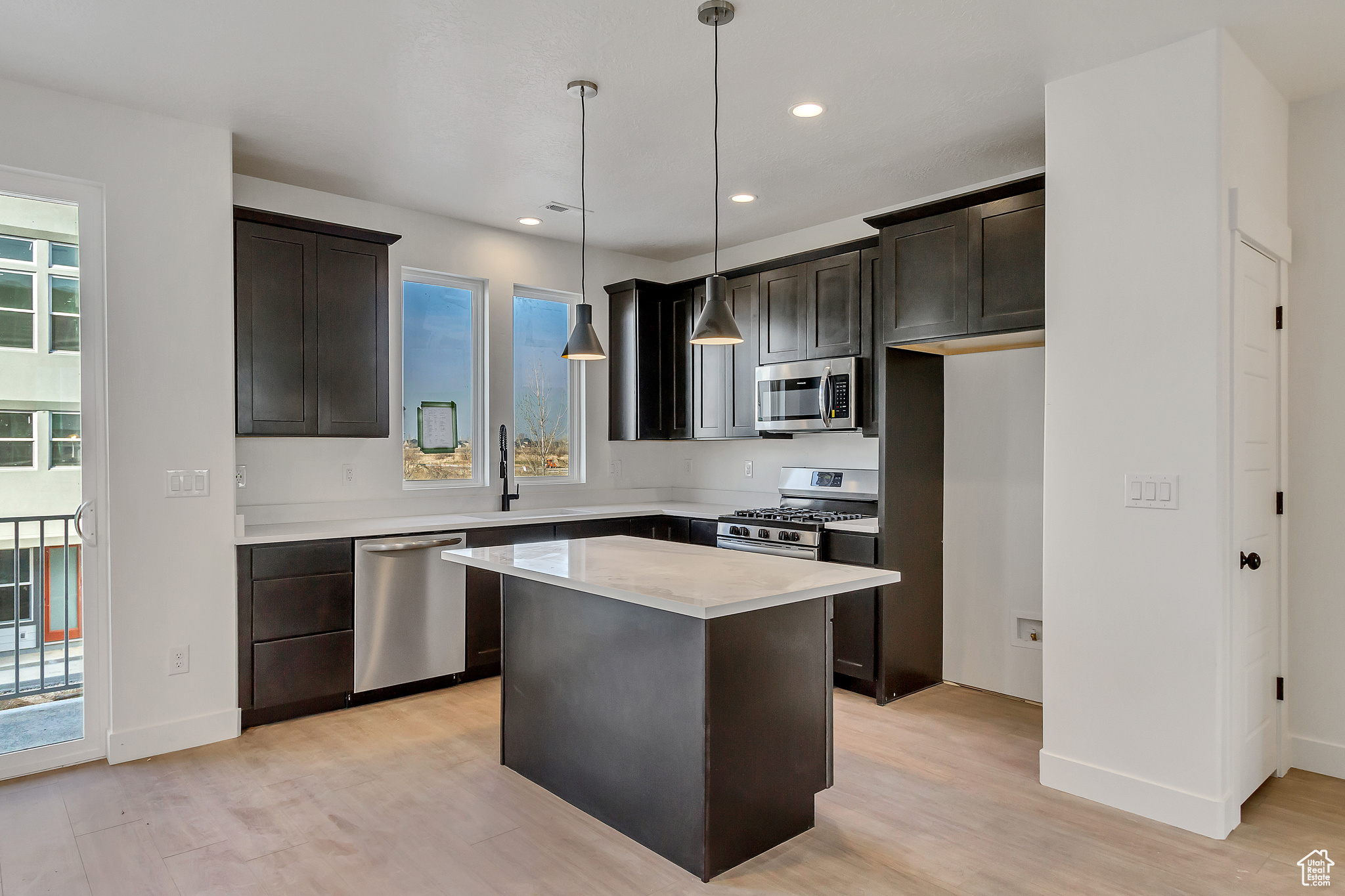Kitchen with a wealth of natural light, appliances with stainless steel finishes, light hardwood / wood-style flooring, and a kitchen island
