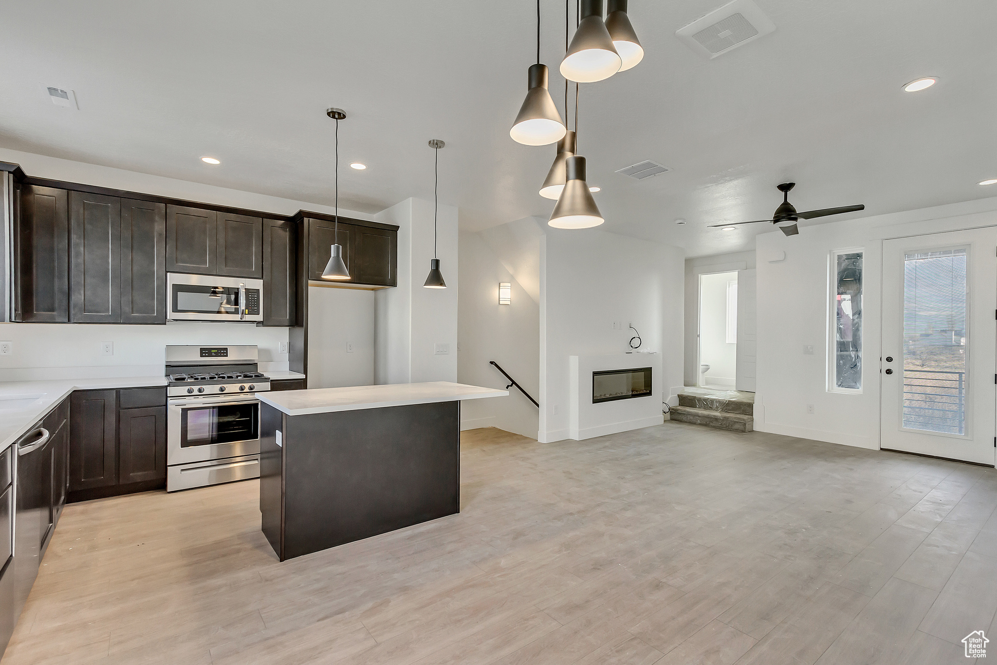 Kitchen featuring a kitchen island, light hardwood / wood-style flooring, stainless steel appliances, ceiling fan, and pendant lighting